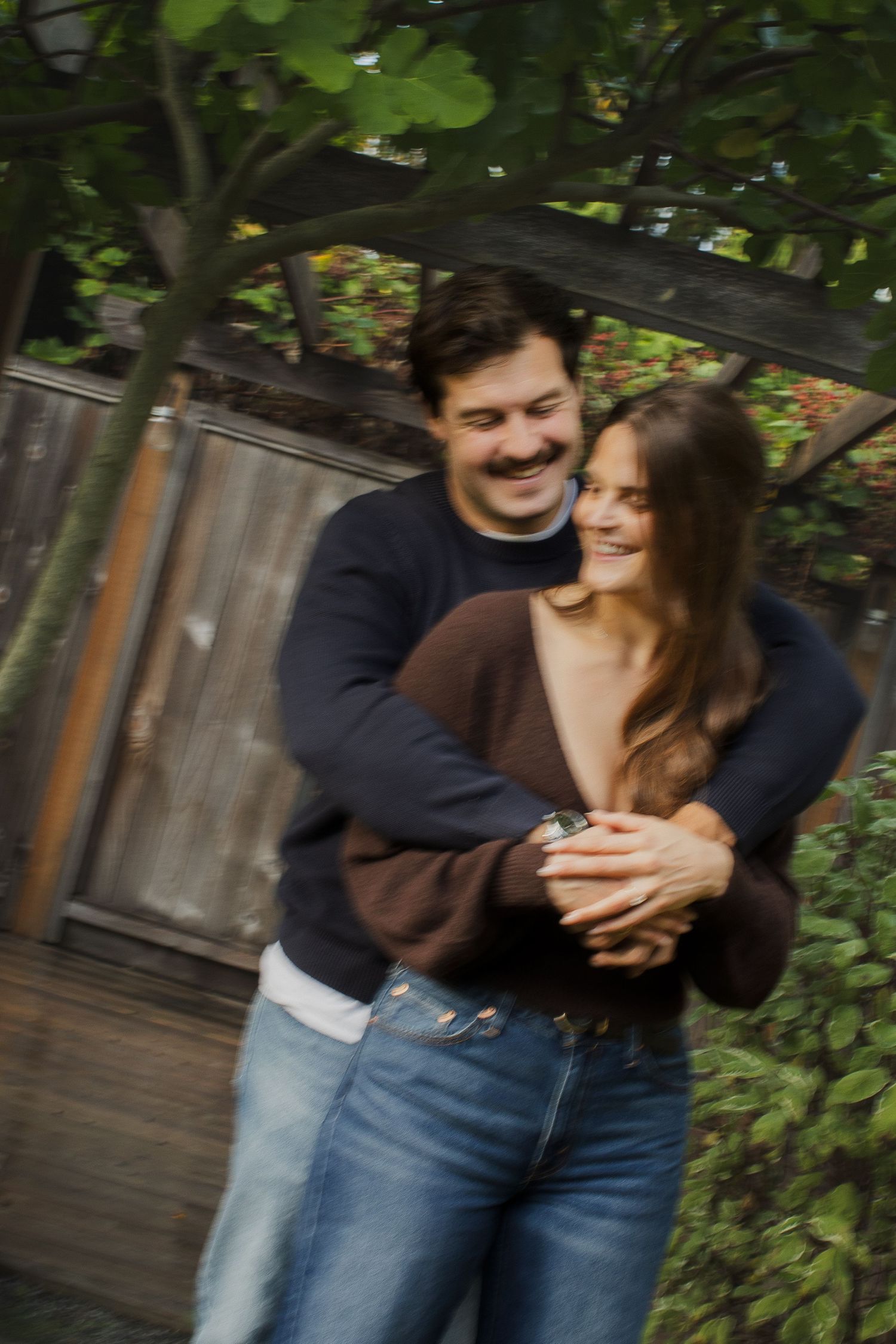 Happy couple embracing and smiling together in a lush backyard garden setting.