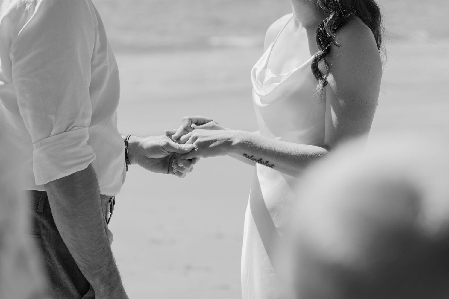 Black and white photo of bride placing wedding ring on grooms hand.