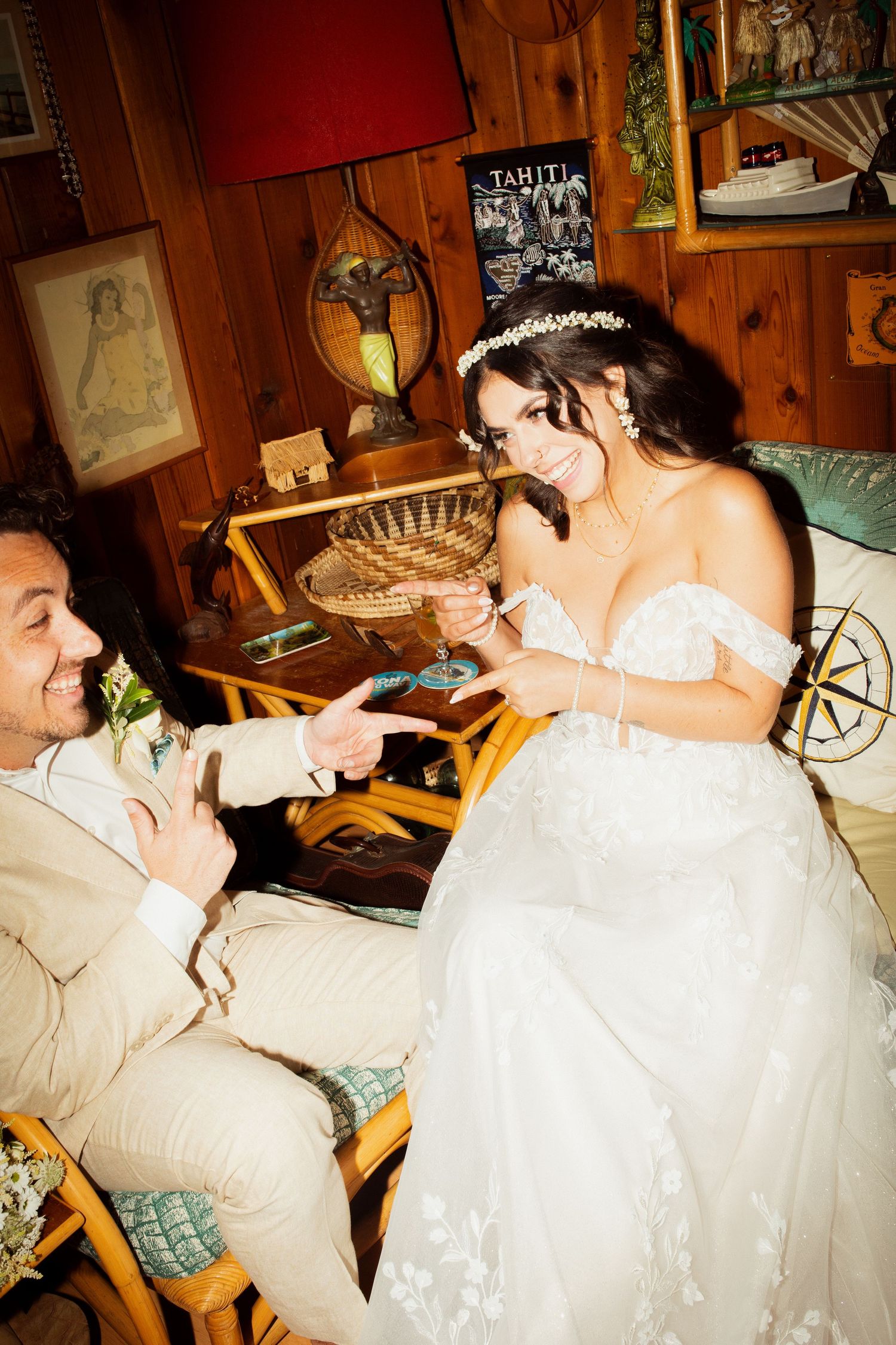 Bride and groom laughing together while seated in rustic decorated indoor wedding venue.