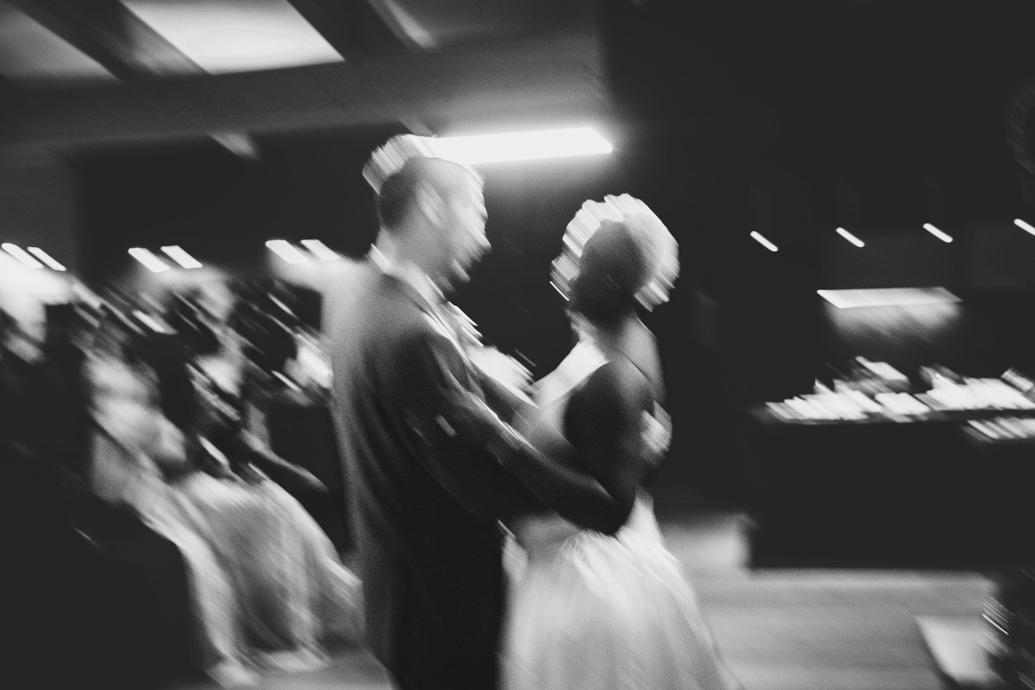 Blurred black and white artistic photo of bride and groom sharing a dance at their reception.