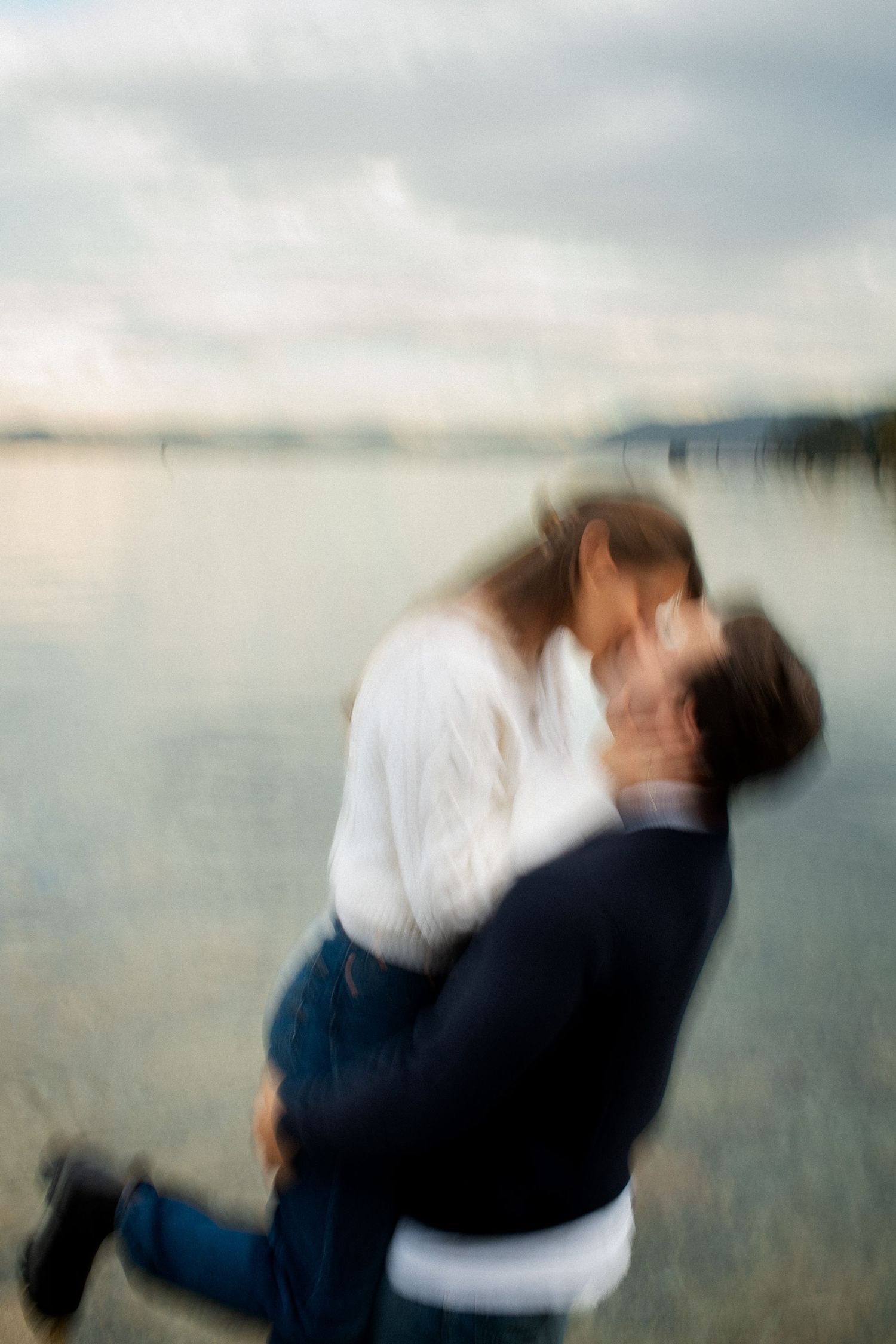 Couple sharing passionate kiss by the lake with artistic motion blur photography effect.