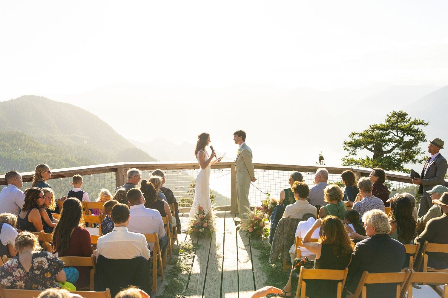 Outdoor mountain wedding ceremony with couple at altar overlooking scenic lake vista.