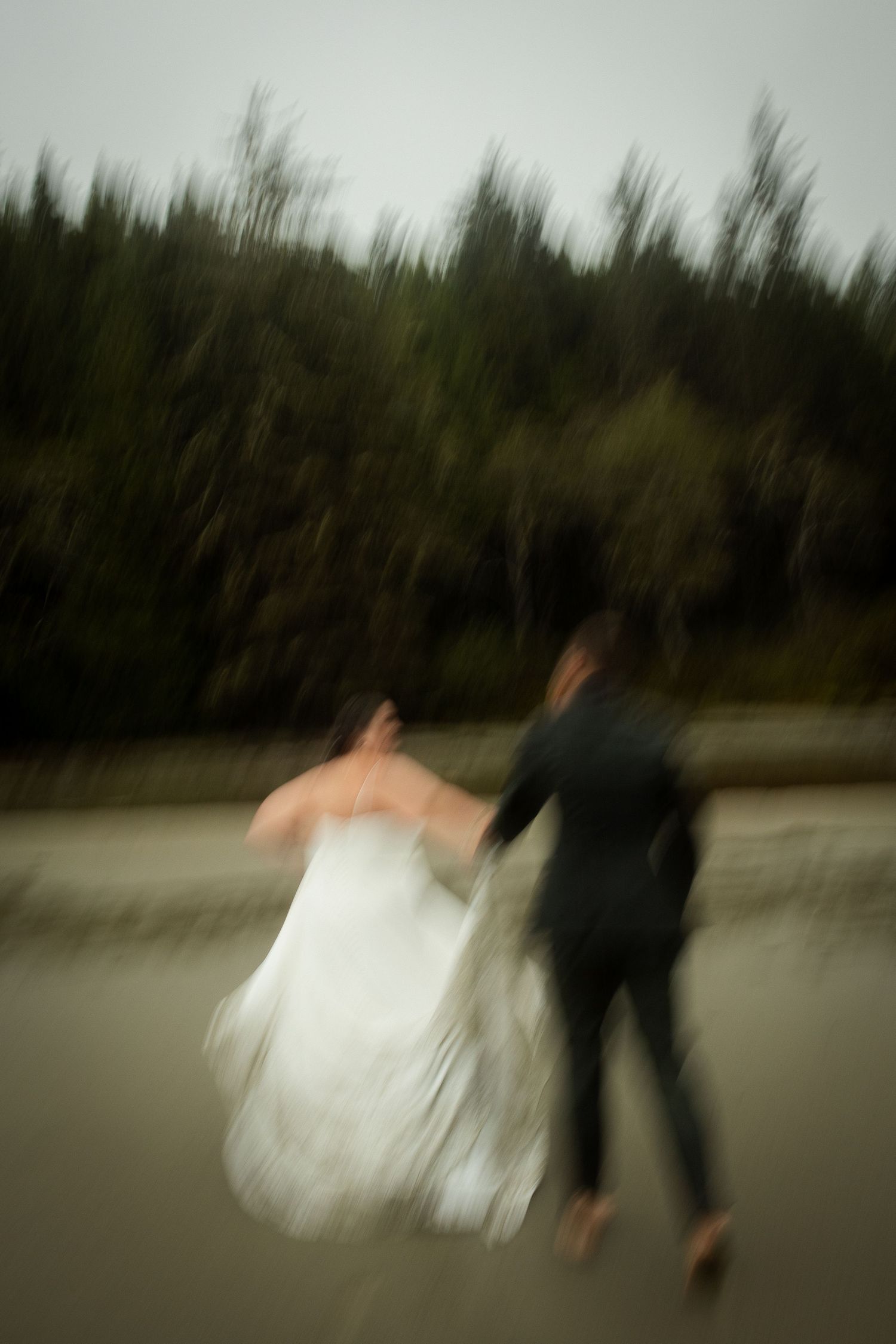 Blurry motion photo of couple running on the beach in the rain