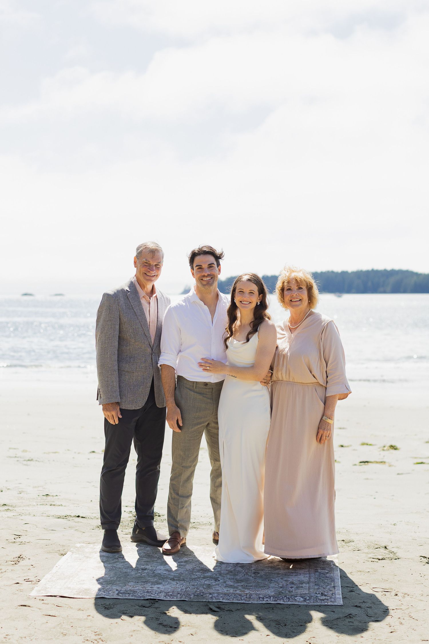 Newlyweds posing with family on beach after intimate wedding ceremony.