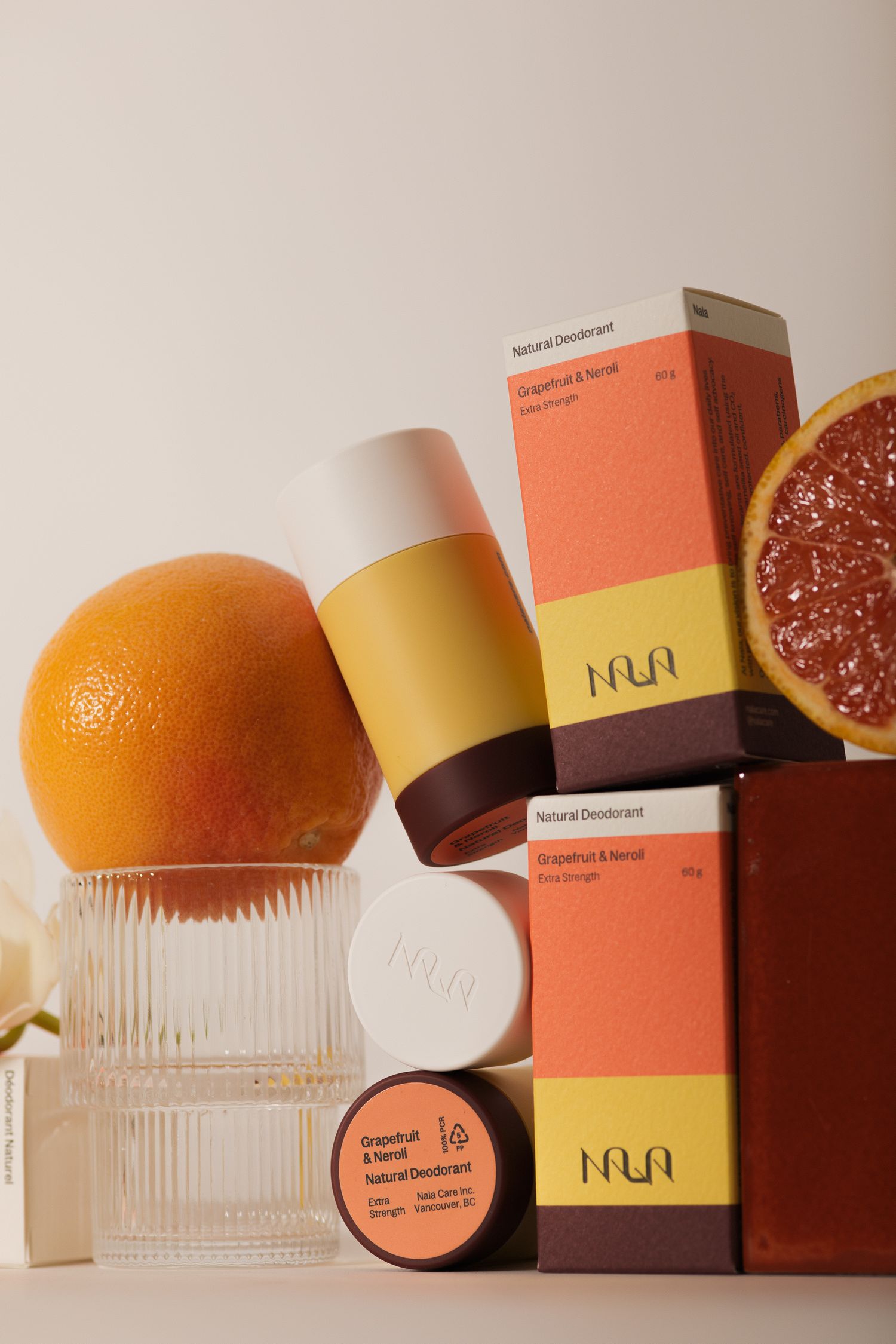 Nala natural deodorant grapefruit and neroli scent displayed with fresh citrus fruits on glass risers.