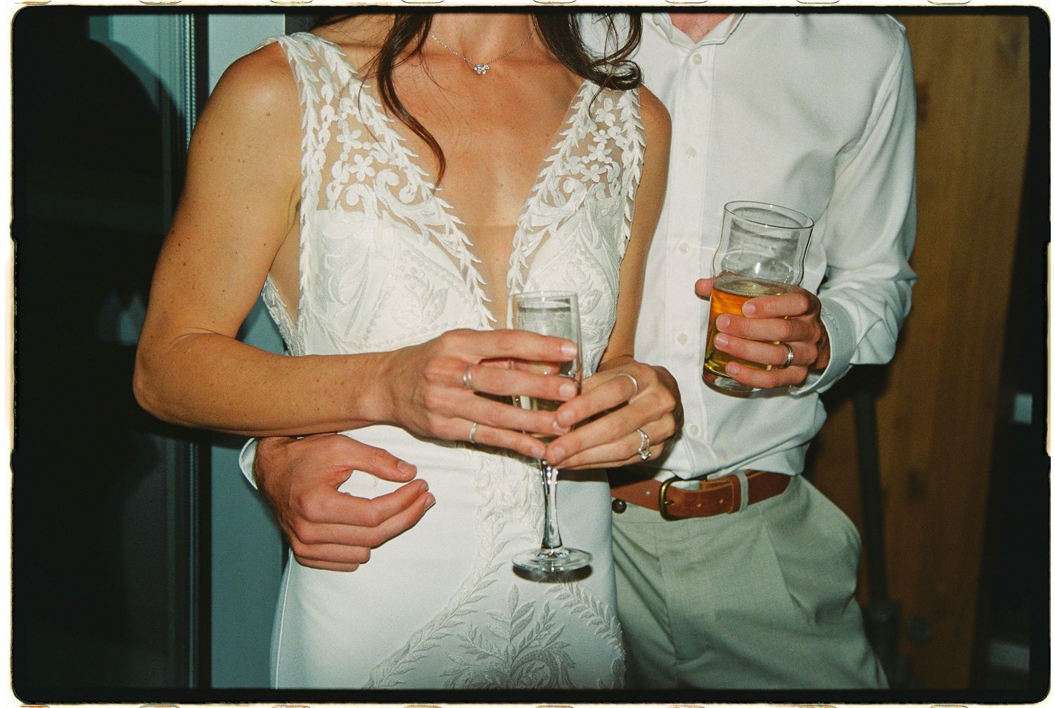 Bride and groom holding champagne glasses together at elegant wedding celebration.