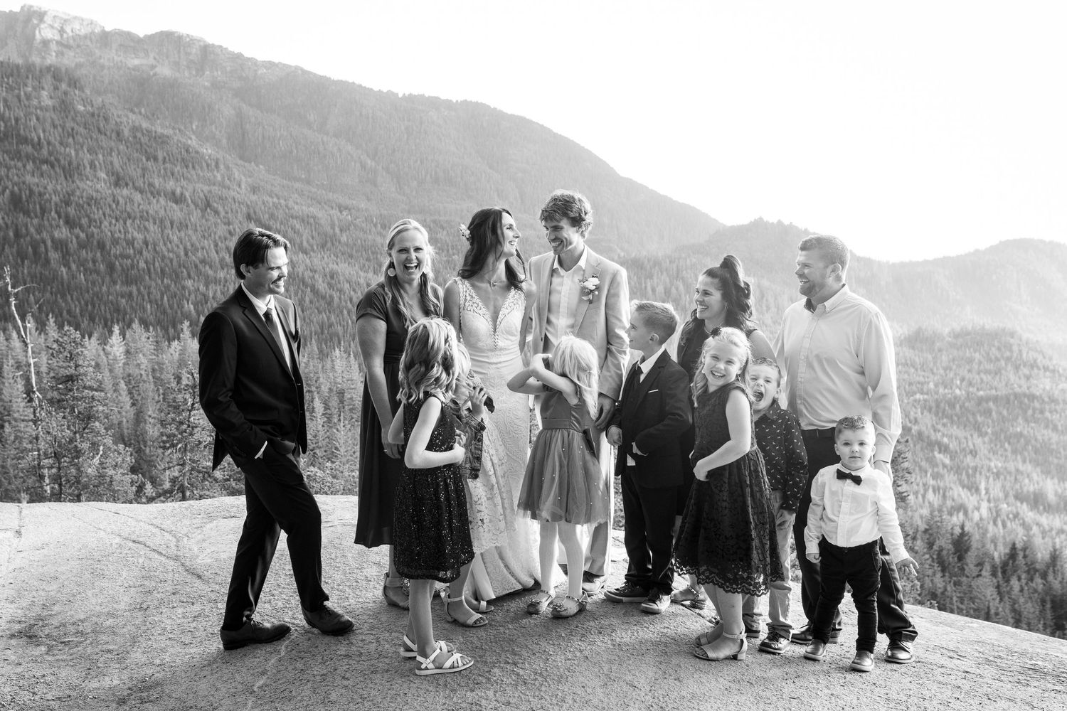 Black and white wedding party portrait with mountains and forest backdrop after ceremony.