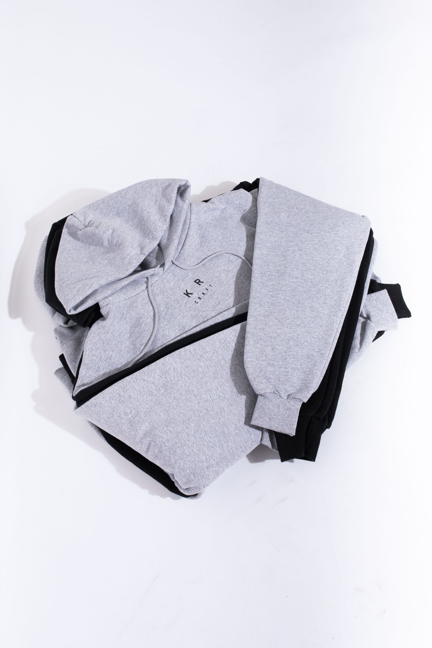 Gray and black color block hoodie and sweatpants set folded on white background.