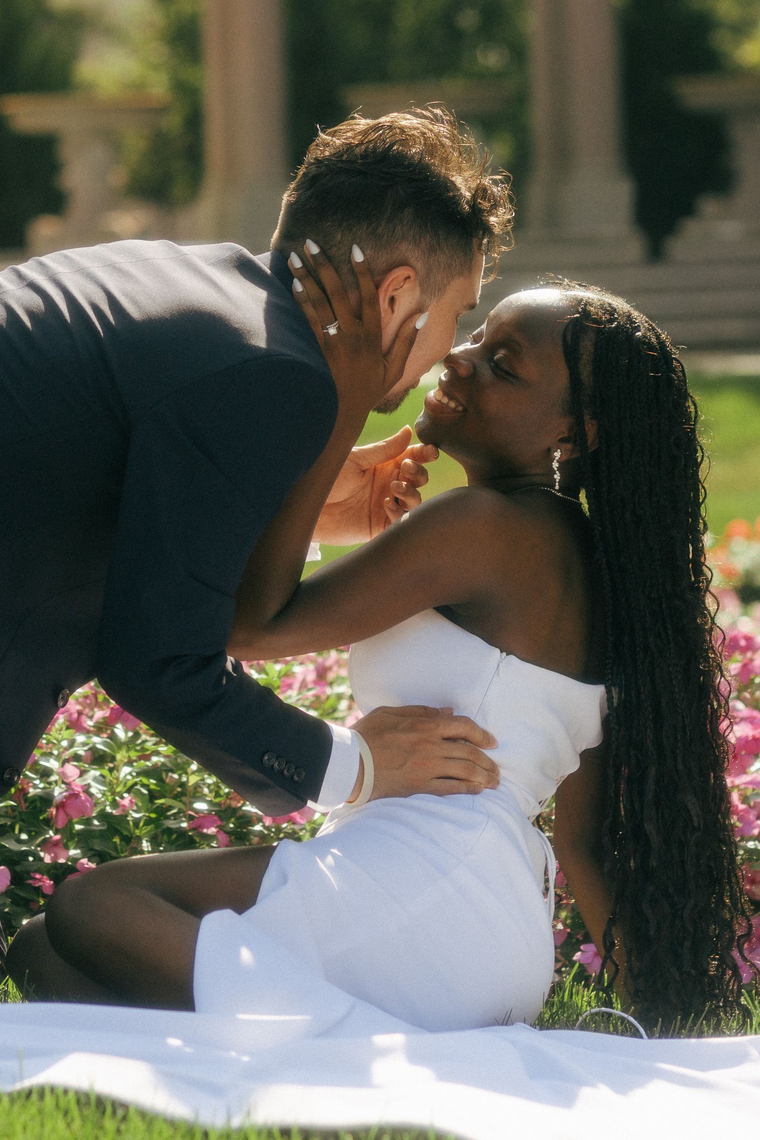 Couple sharing a romantic kiss in a garden, bride in white dress and groom in dark suit.