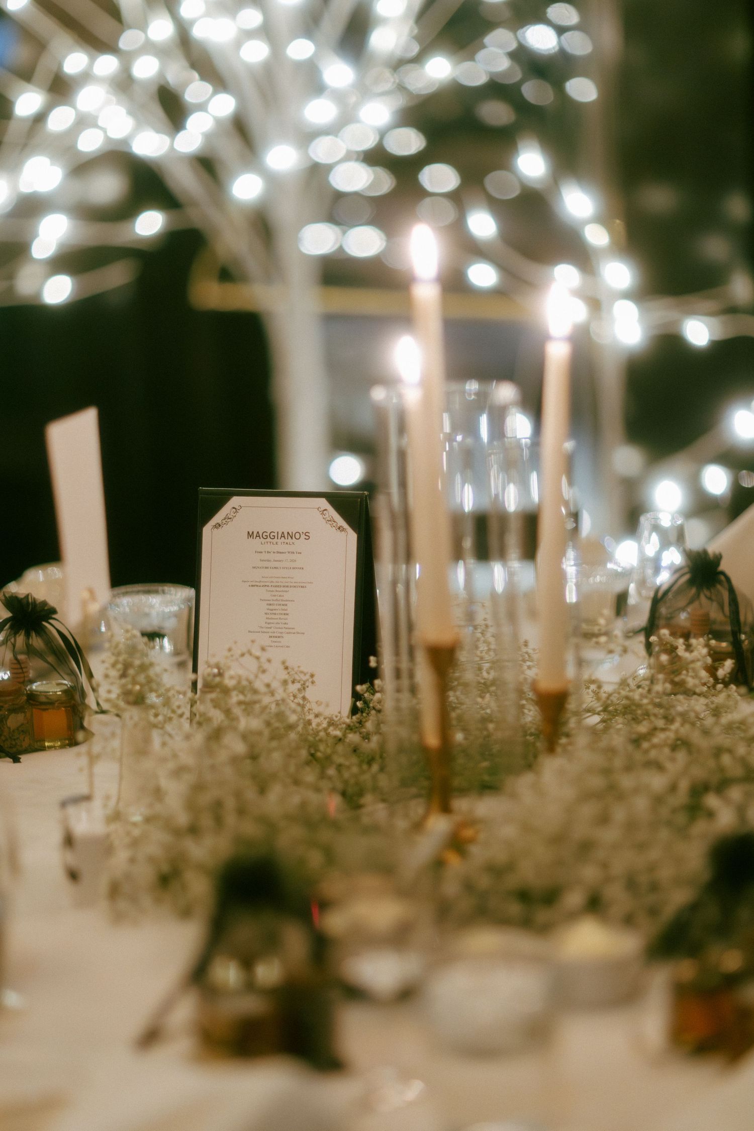 Elegant wedding reception table with tall candles, baby's breath, and string lights creating a romantic ambiance.