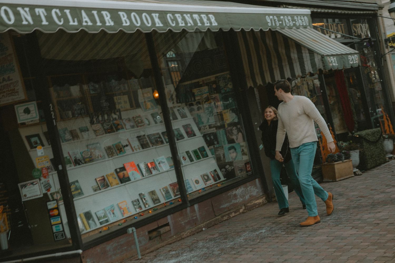 Couple walking hand in hand outside Montclair Book Centre storefront with large display windows.