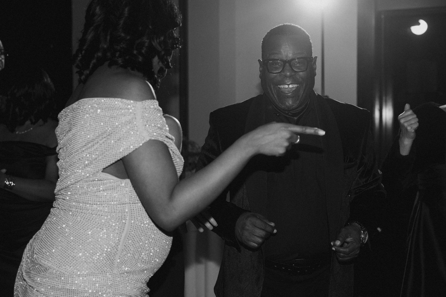 Couple dancing joyfully at a formal event in black and white photo.