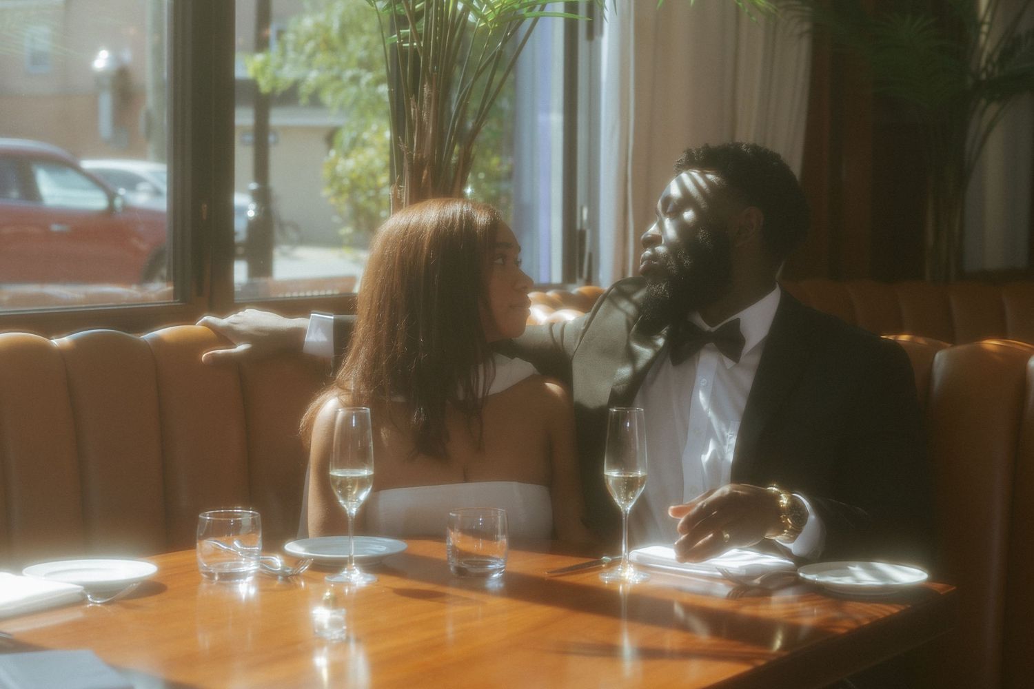 Stylish Black couple in formal attire sharing a romantic dinner at an upscale restaurant.