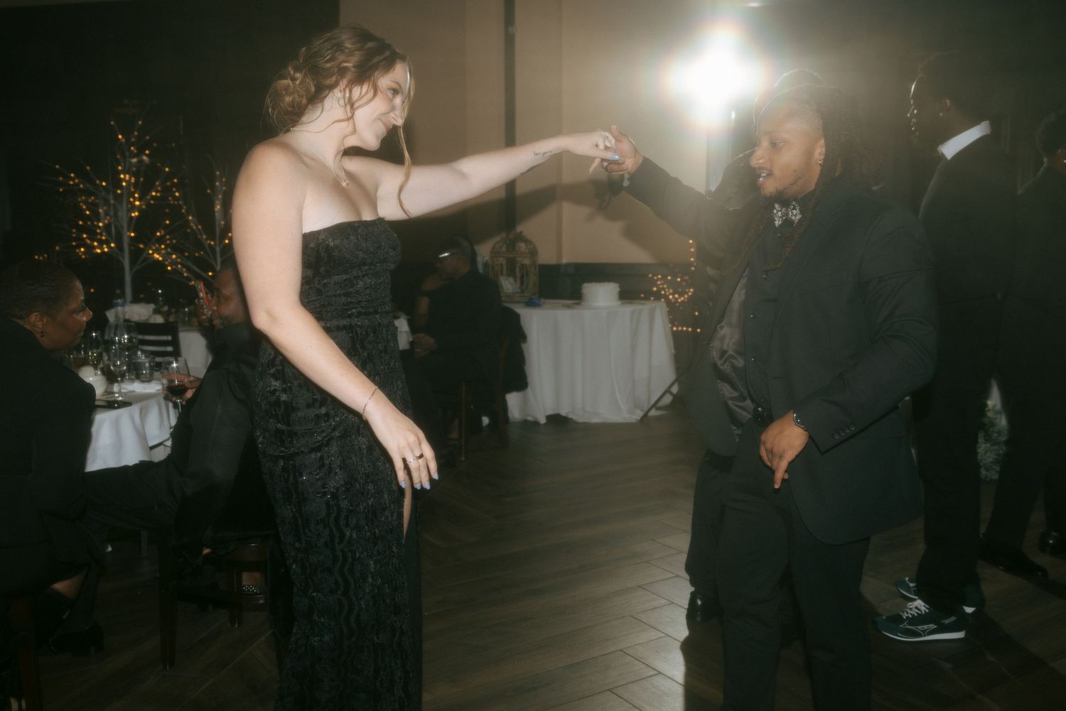 Couple dancing elegantly at a formal wedding reception in a dimly lit venue.