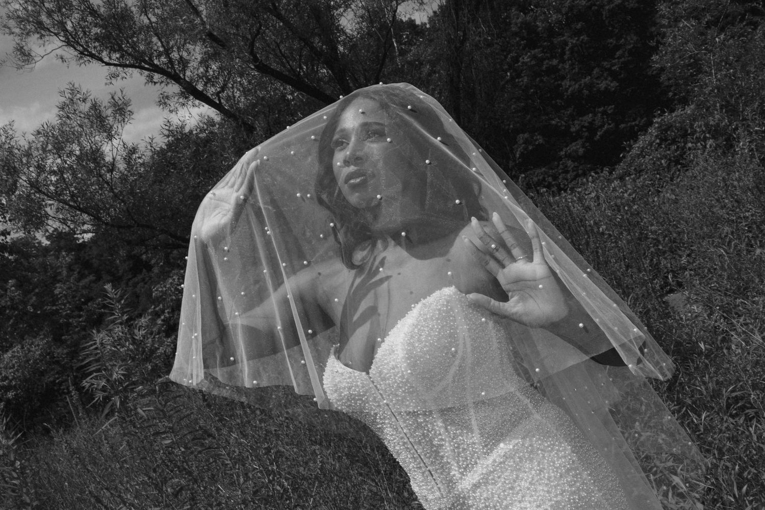 Black and white photo of bride in pearl veil and sparkle gown outdoors.