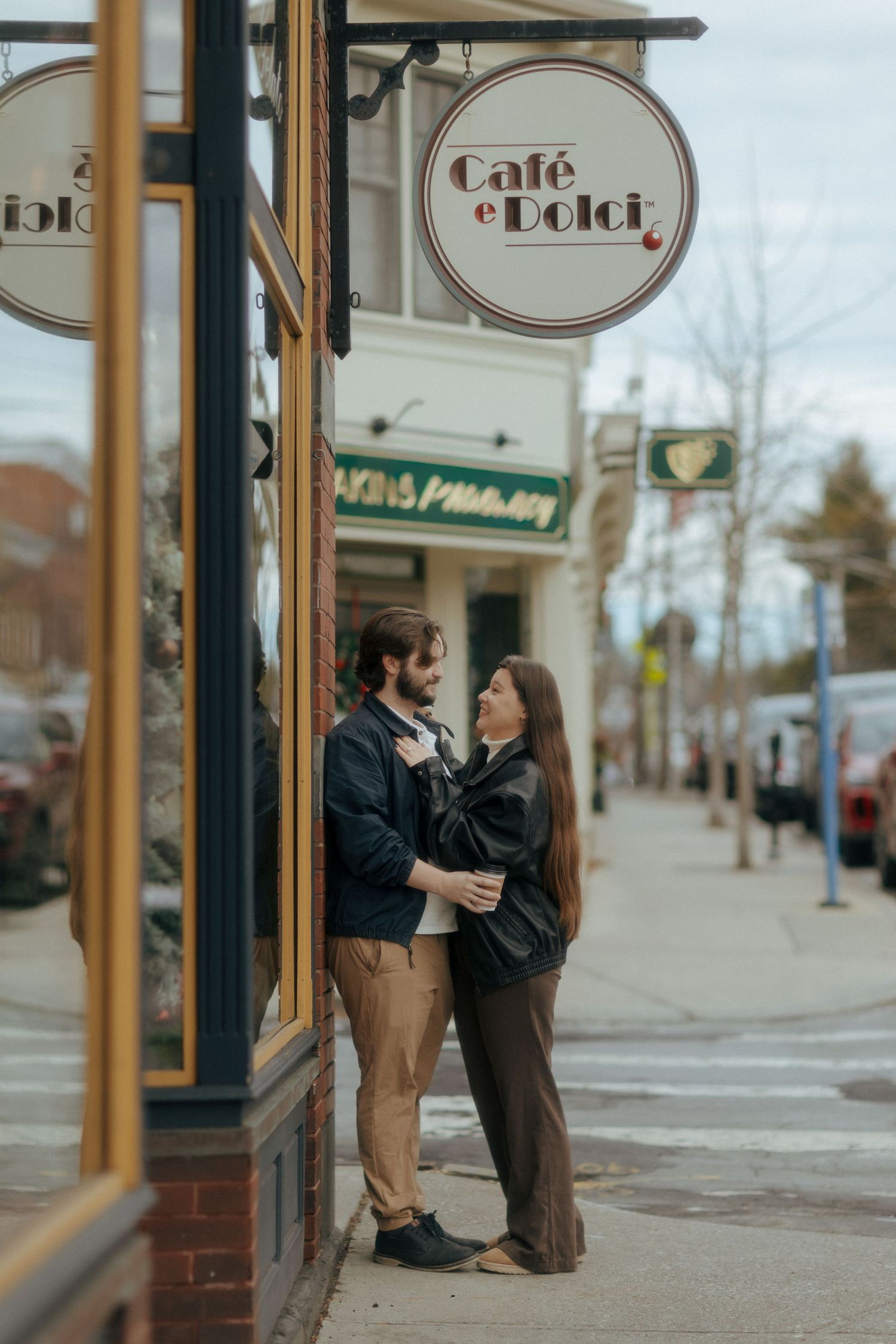 Couple sharing a romantic moment outside Café e Dolci on a charming small-town street sidewalk.