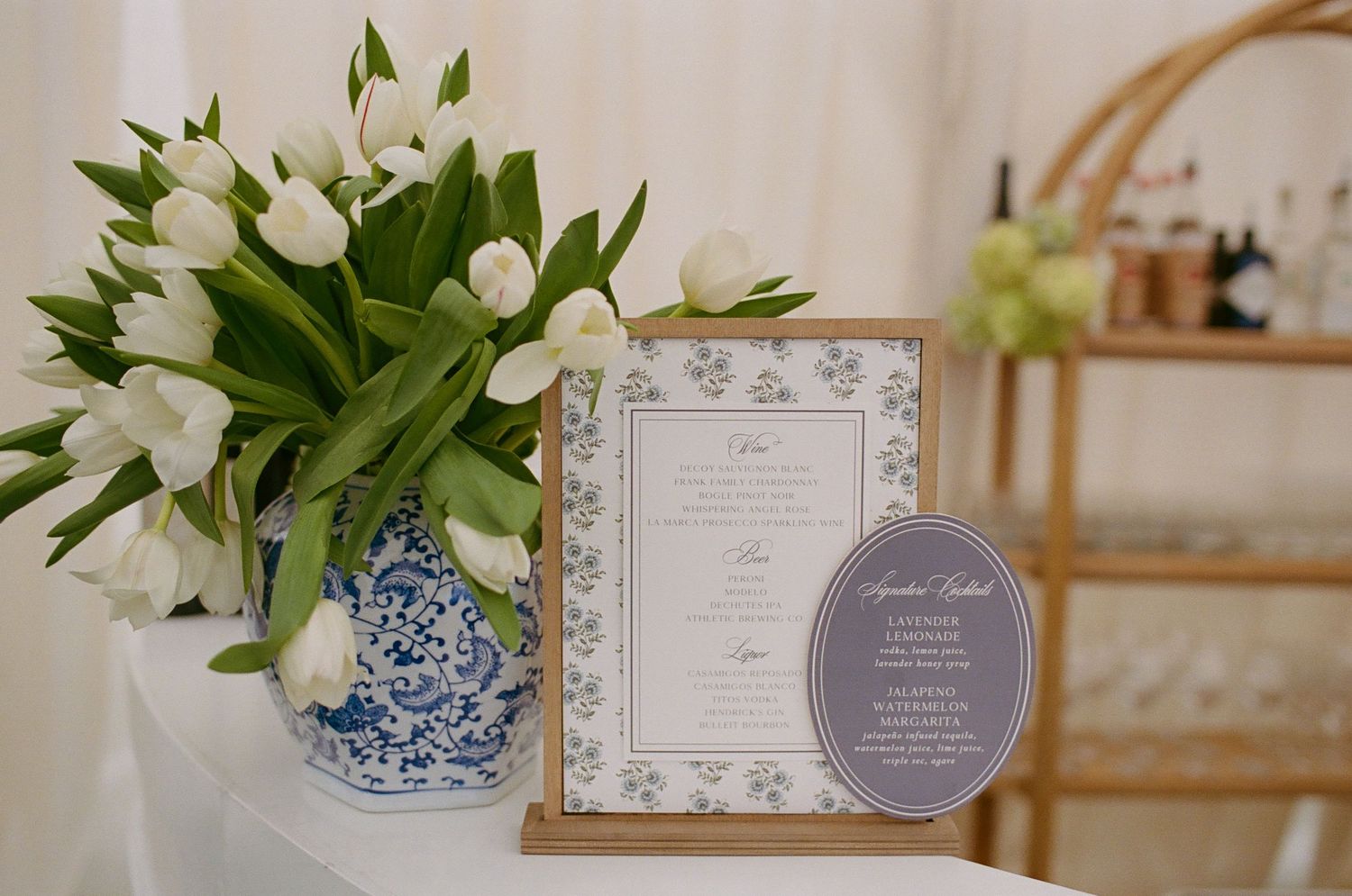 White tulips and lilies in blue and white porcelain vases with wedding stationery on display.