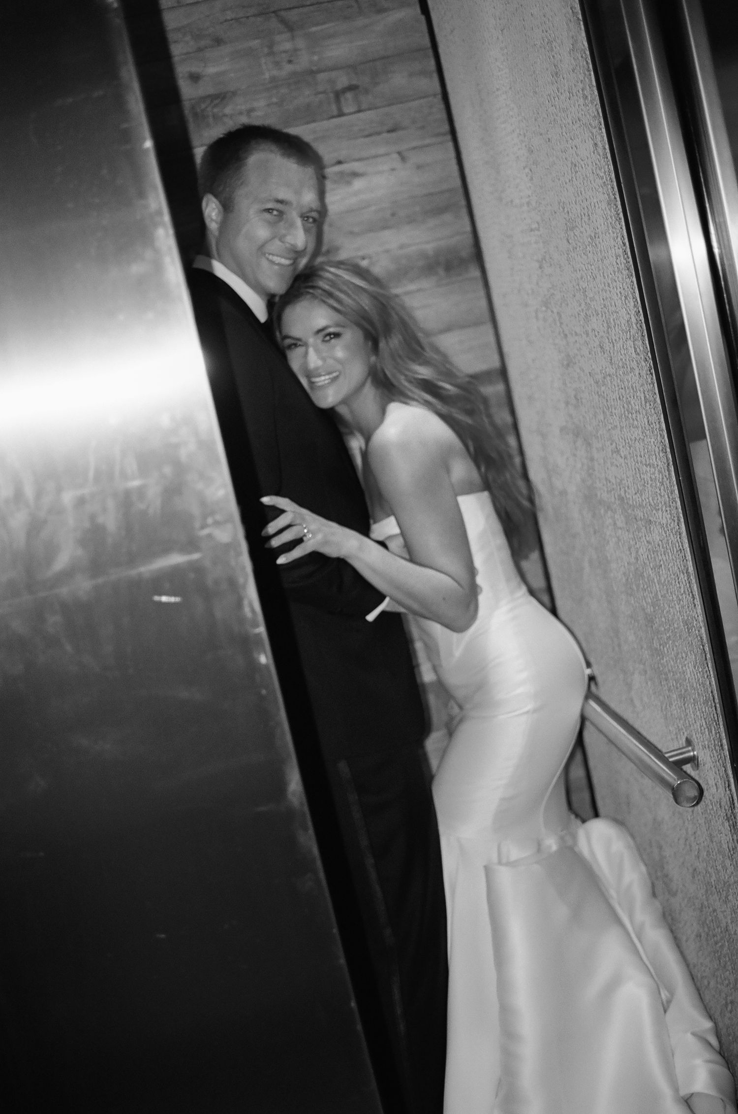 Couple sharing joyful moments in an elevator on their wedding day.