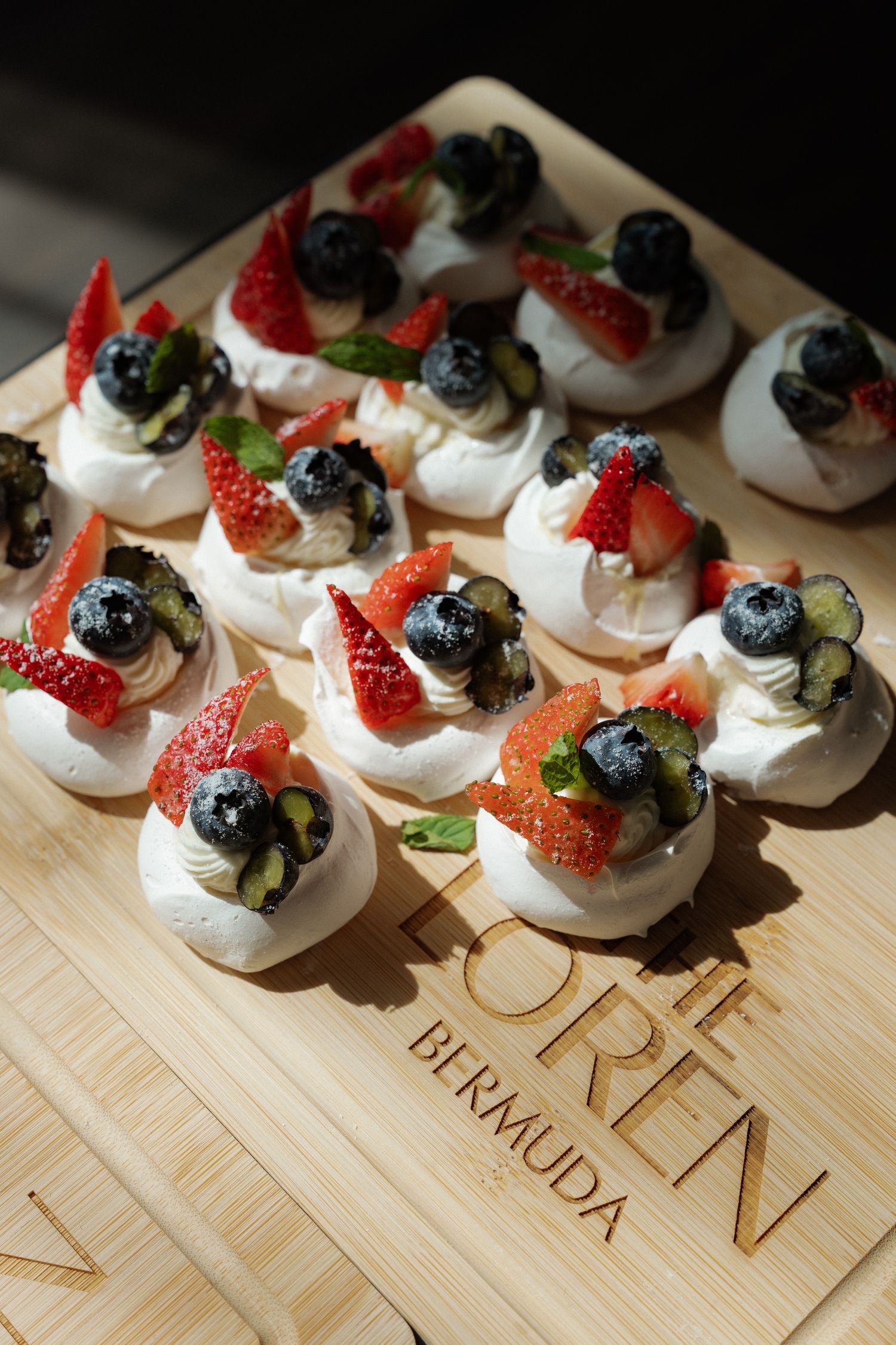 A plate of small dessert bites topped with fresh berries and mint leaves.