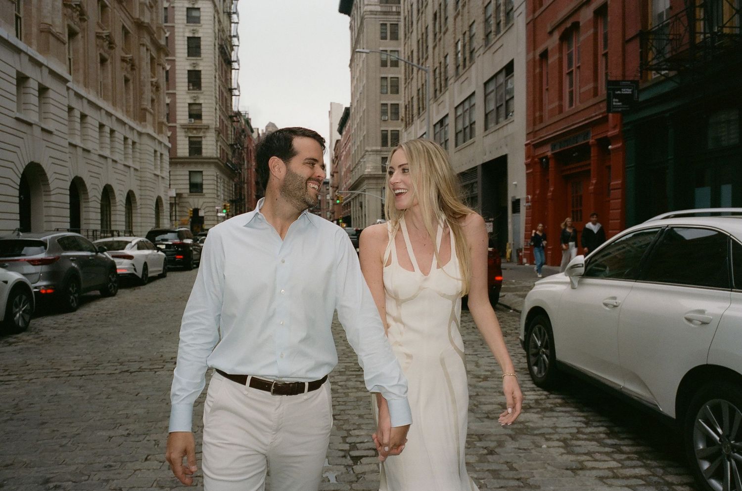 A couple strolls together on a cobblestone street surrounded by historic architecture.