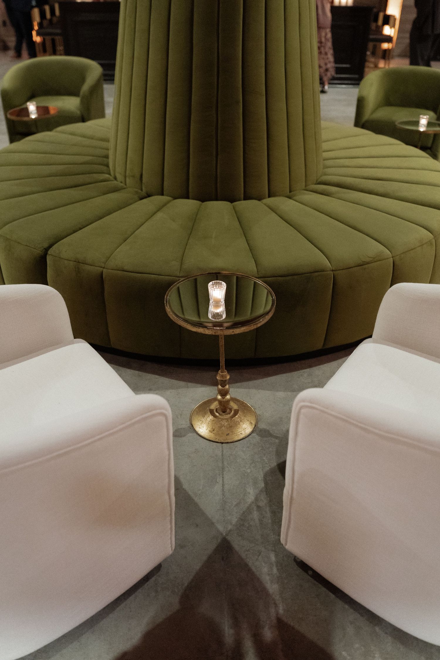 Modern lounge area featuring olive green circular seating and white accent furniture.