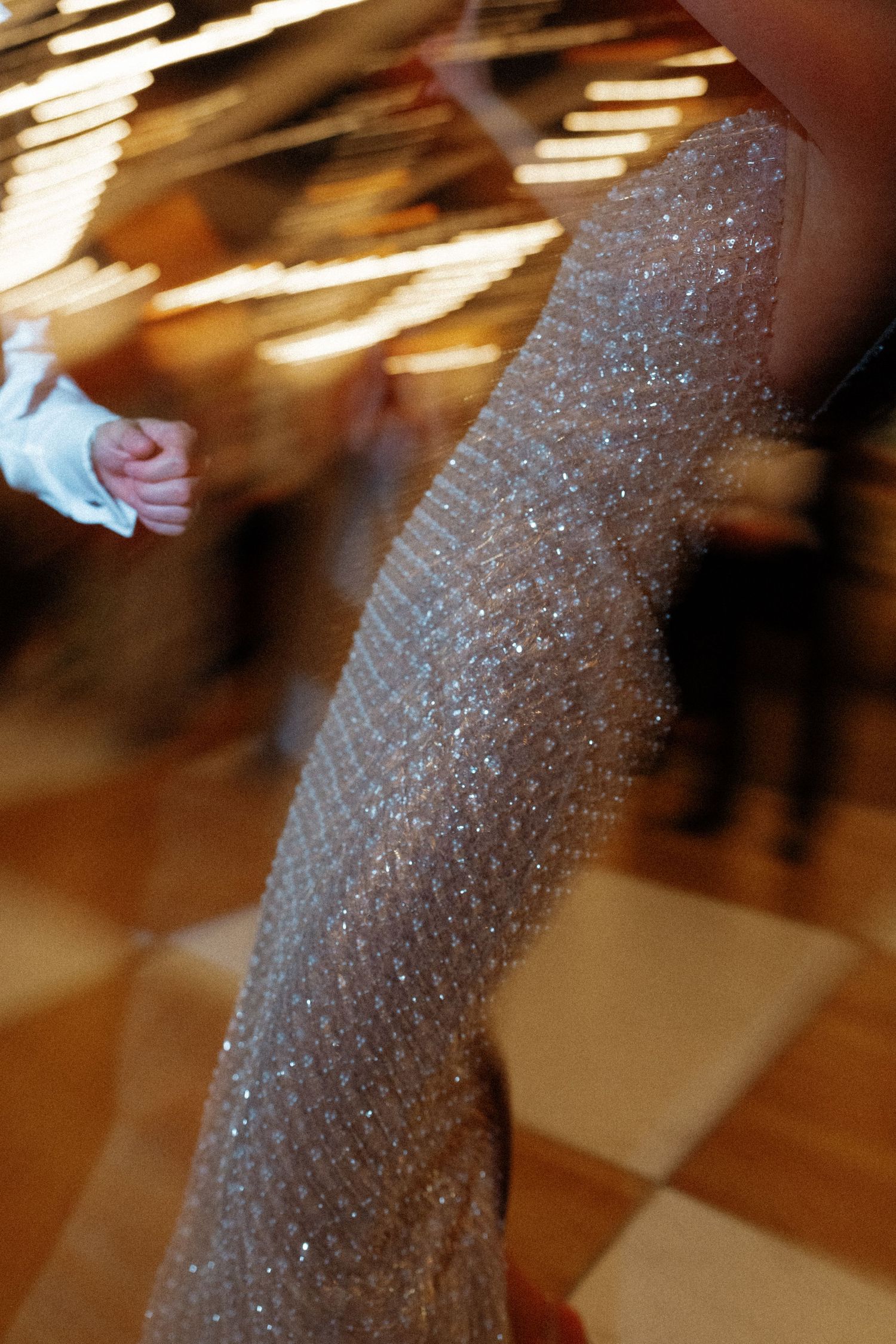 Blurred motion shot of sparkling sequin gown being worn by dancer on checkered dance floor at event.