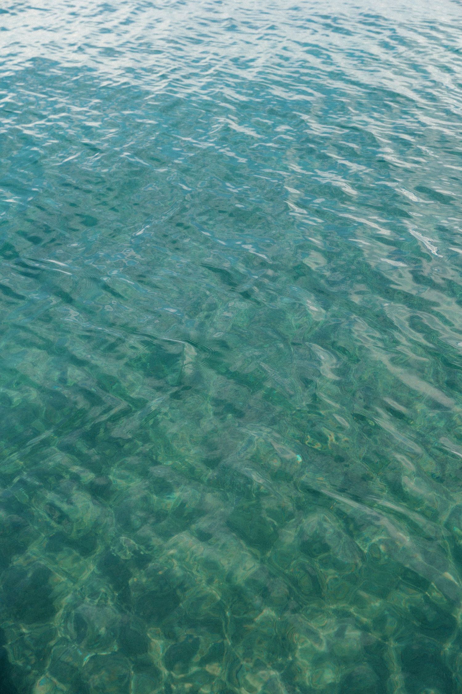 Crystal clear turquoise water rippling with sunlight creating patterns beneath the surface.