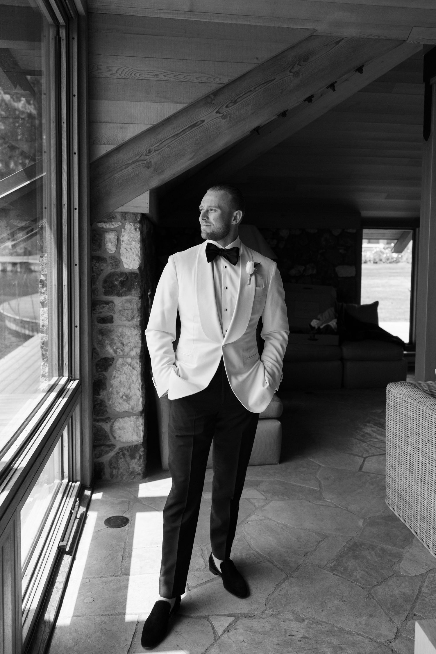 Black and white photo showing formal attire details with white jacket and black pants in shadowy lighting.