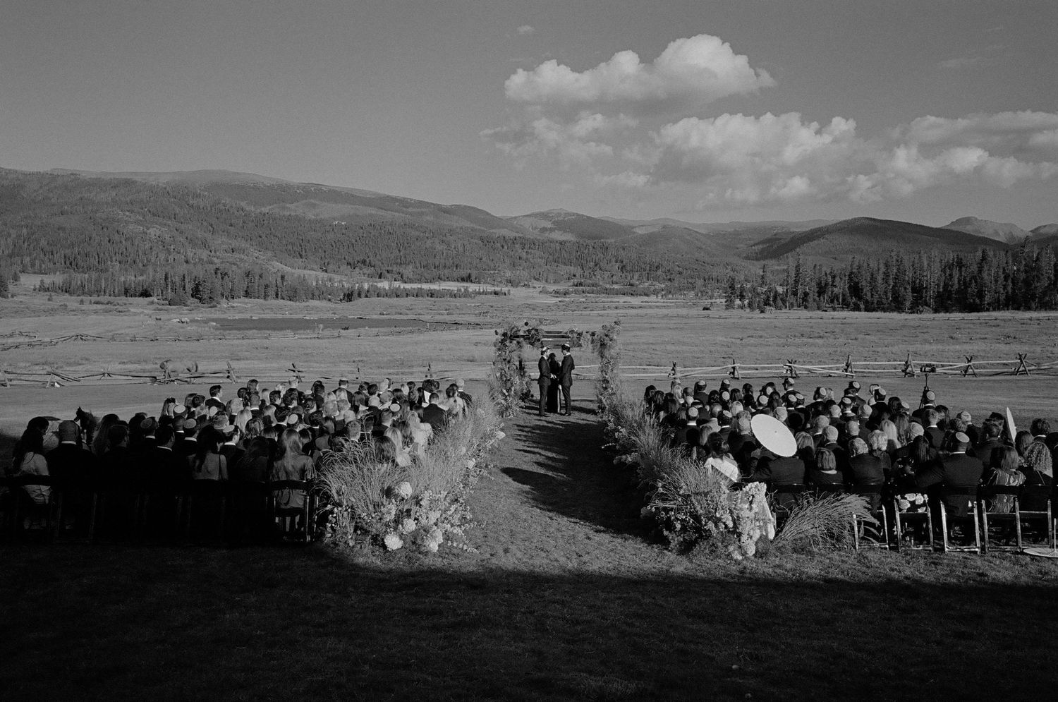 Black and white panoramic landscape view of mountains and rolling hills under cloudy skies.