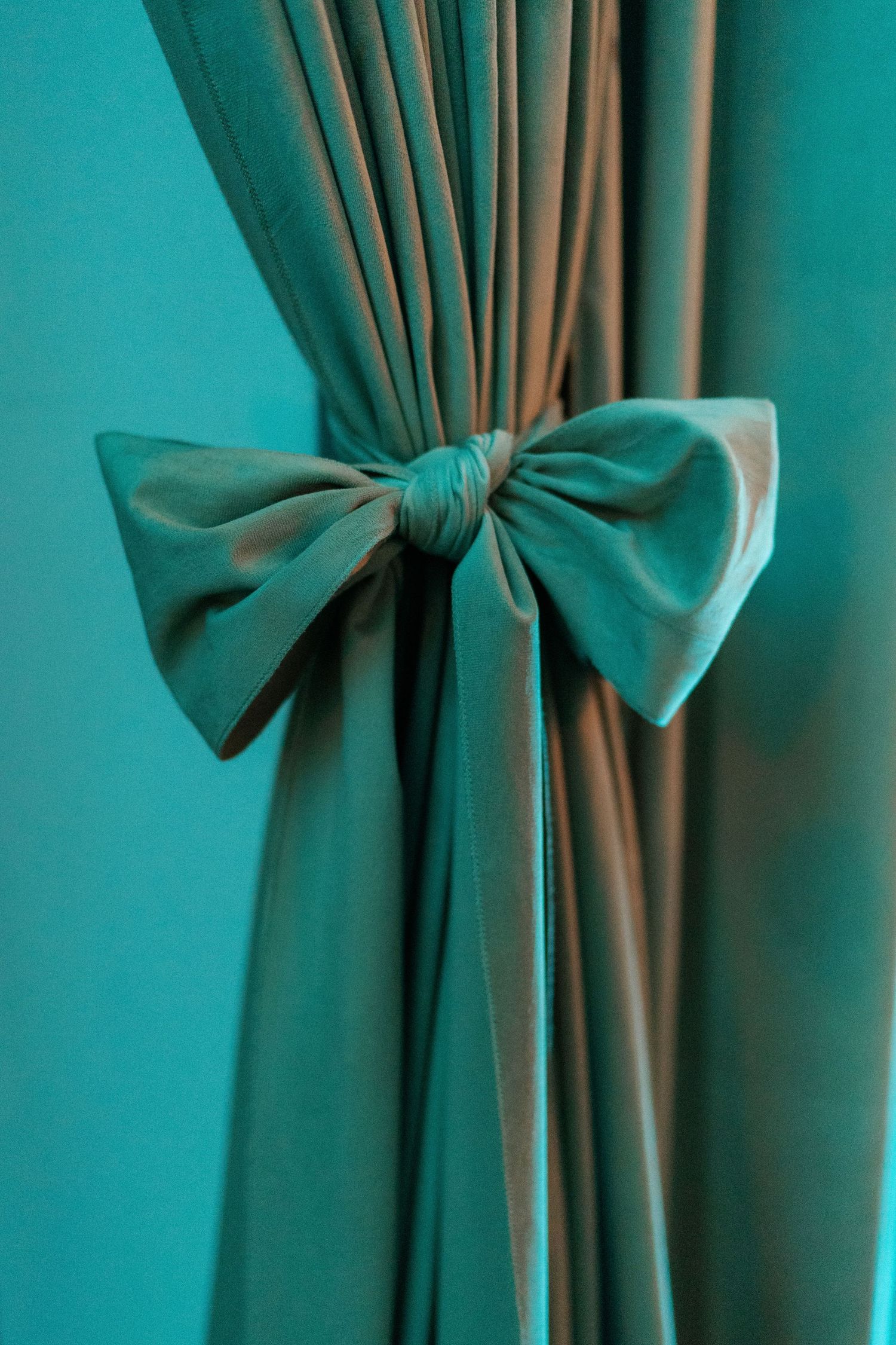 Teal curtains with elegant bows creating a decorative window treatment.
