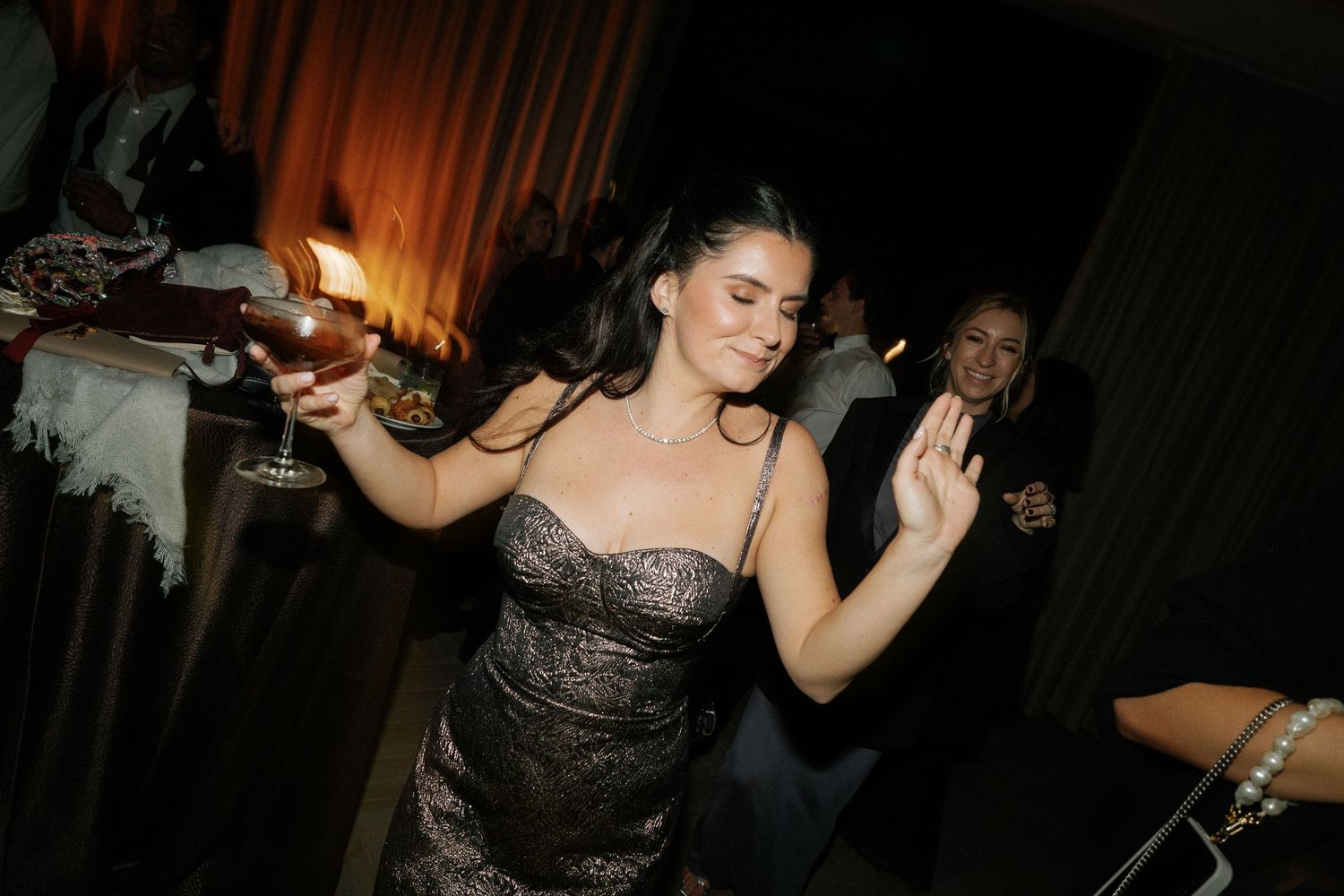 Guests dancing enthusiastically at a dimly lit wedding reception celebration.