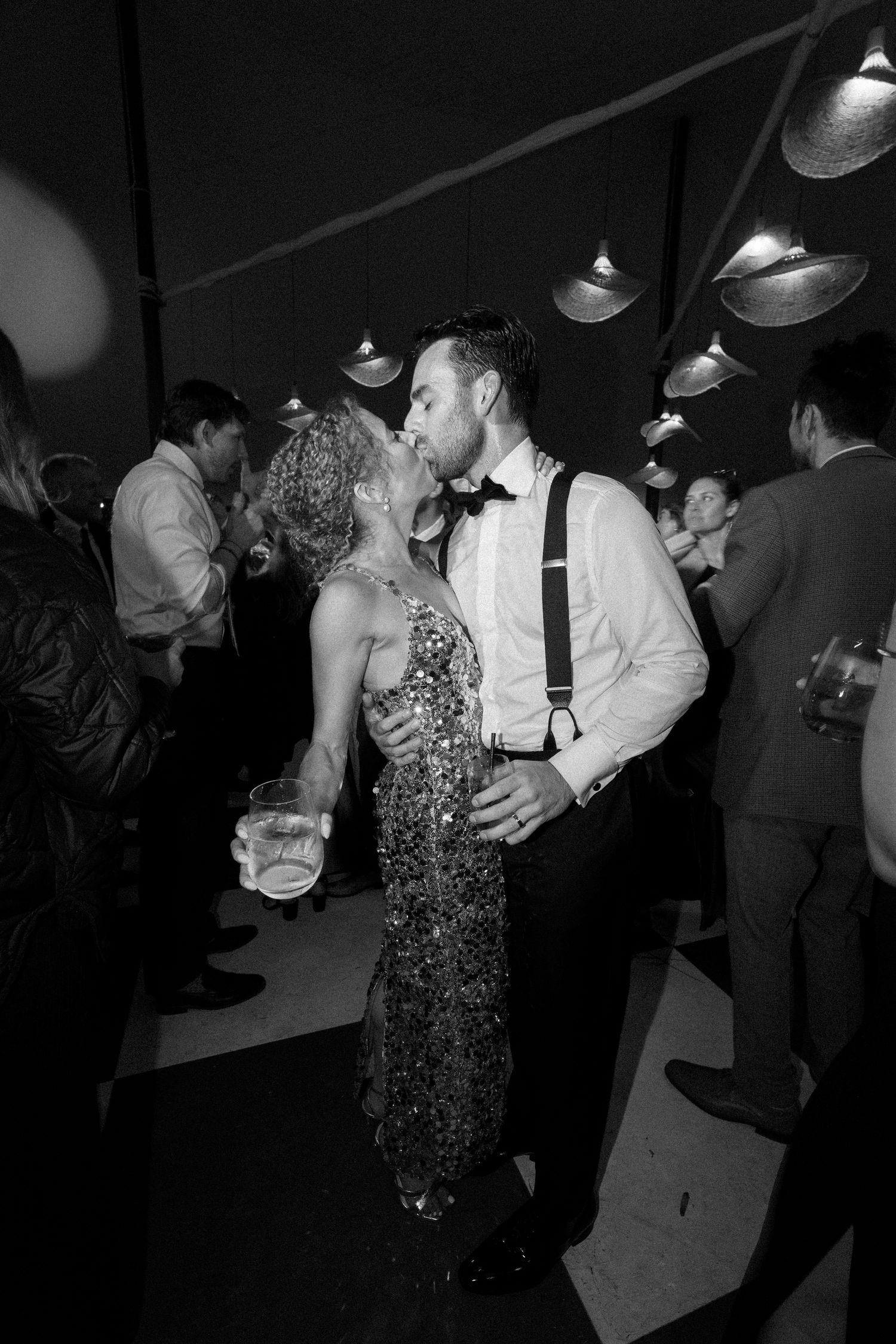 Couples slow dancing in formal attire at a dimly lit reception.