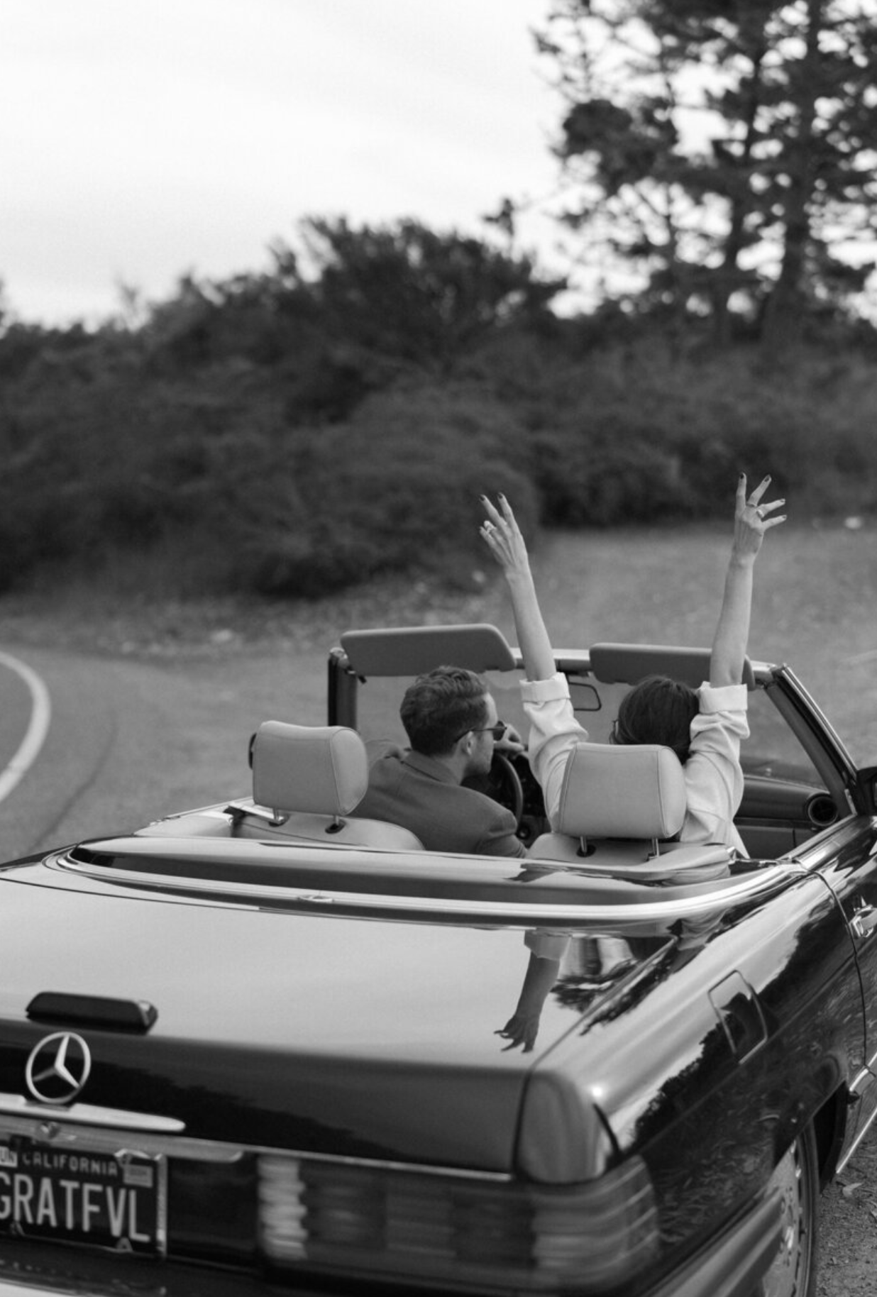 Hands raised joyfully from a convertible car during a celebration.