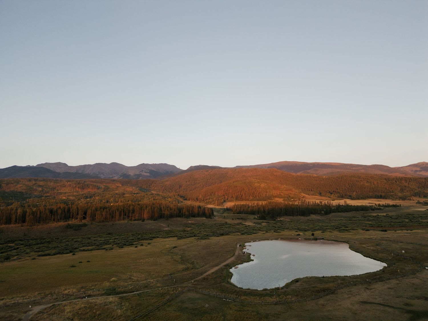Panoramic mountain landscape with a serene lake at sunset.