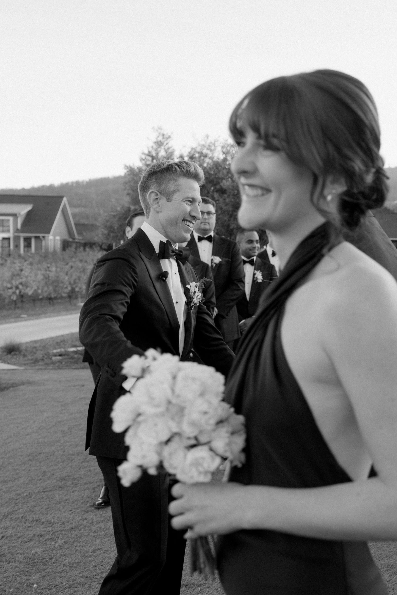 Black and white wedding photo showing joyful moments between a couple with a white bouquet.