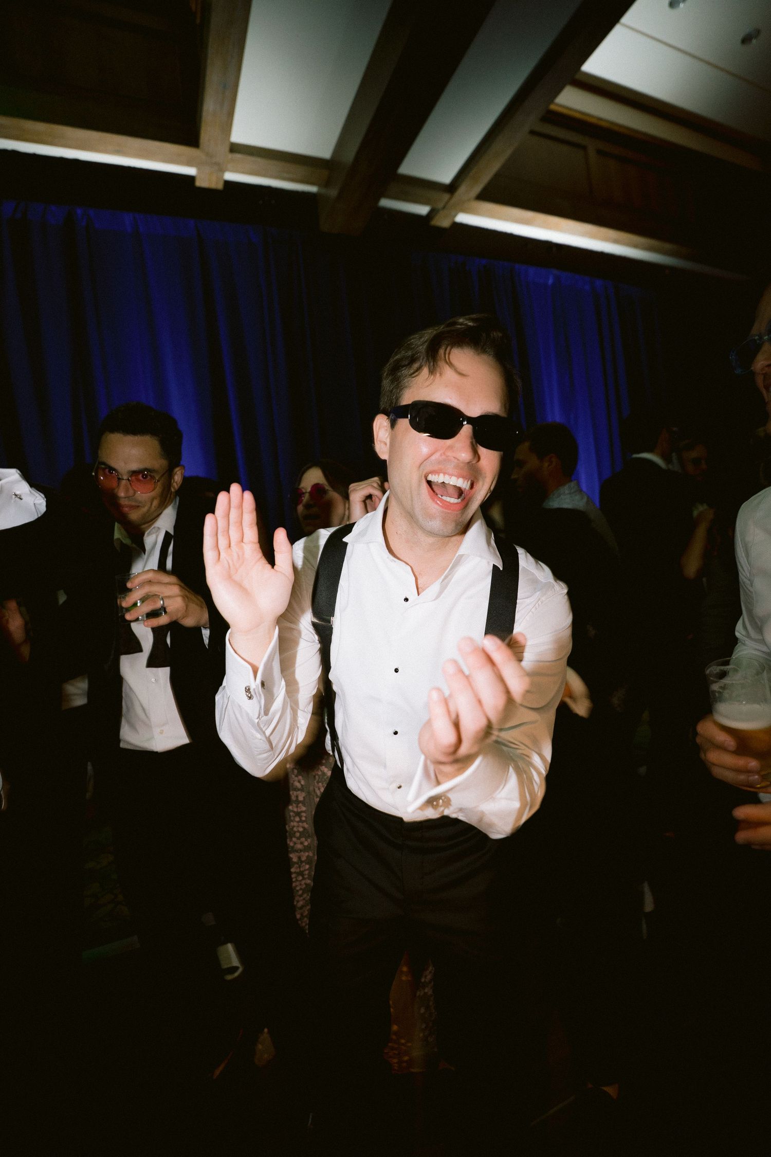 Energetic party scene with people dancing and celebrating under blue lighting.