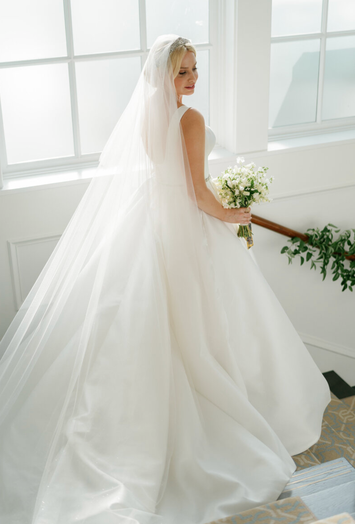 Ethereal bridal portraits showing flowing white wedding gown in a bright, window-lit room.