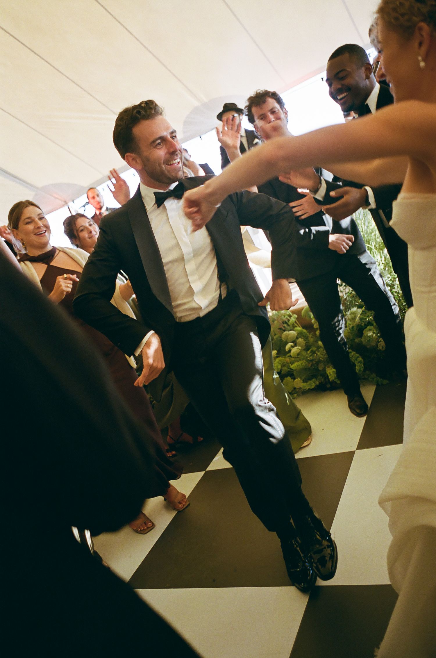 Wedding party dancing and celebrating in formal attire at indoor reception.