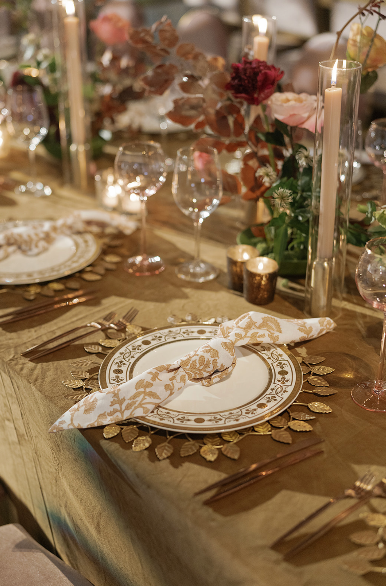 Elegant wedding table setting with gold accents, candles, and floral arrangements.