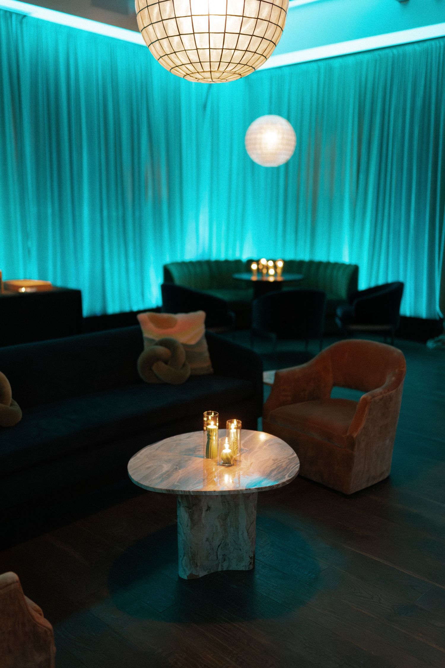 Luxurious lounge space with turquoise uplighting and paper lantern fixtures.