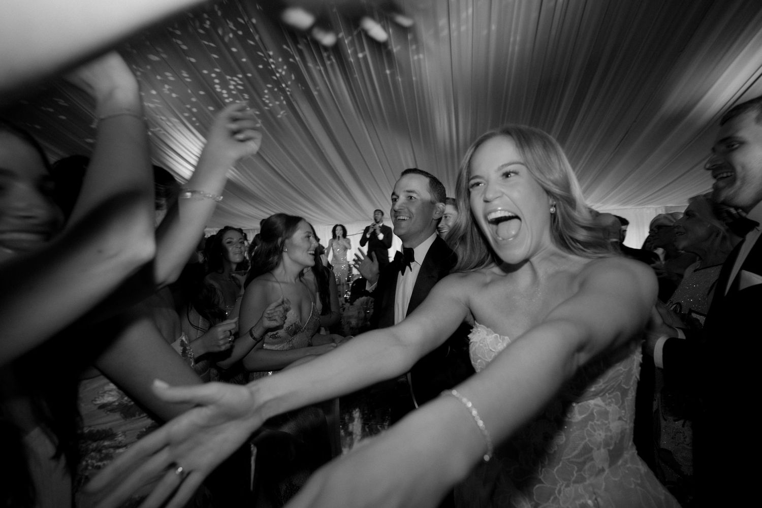 Wedding reception guests dancing and celebrating on a dimly lit dance floor with dramatic lighting effects.
