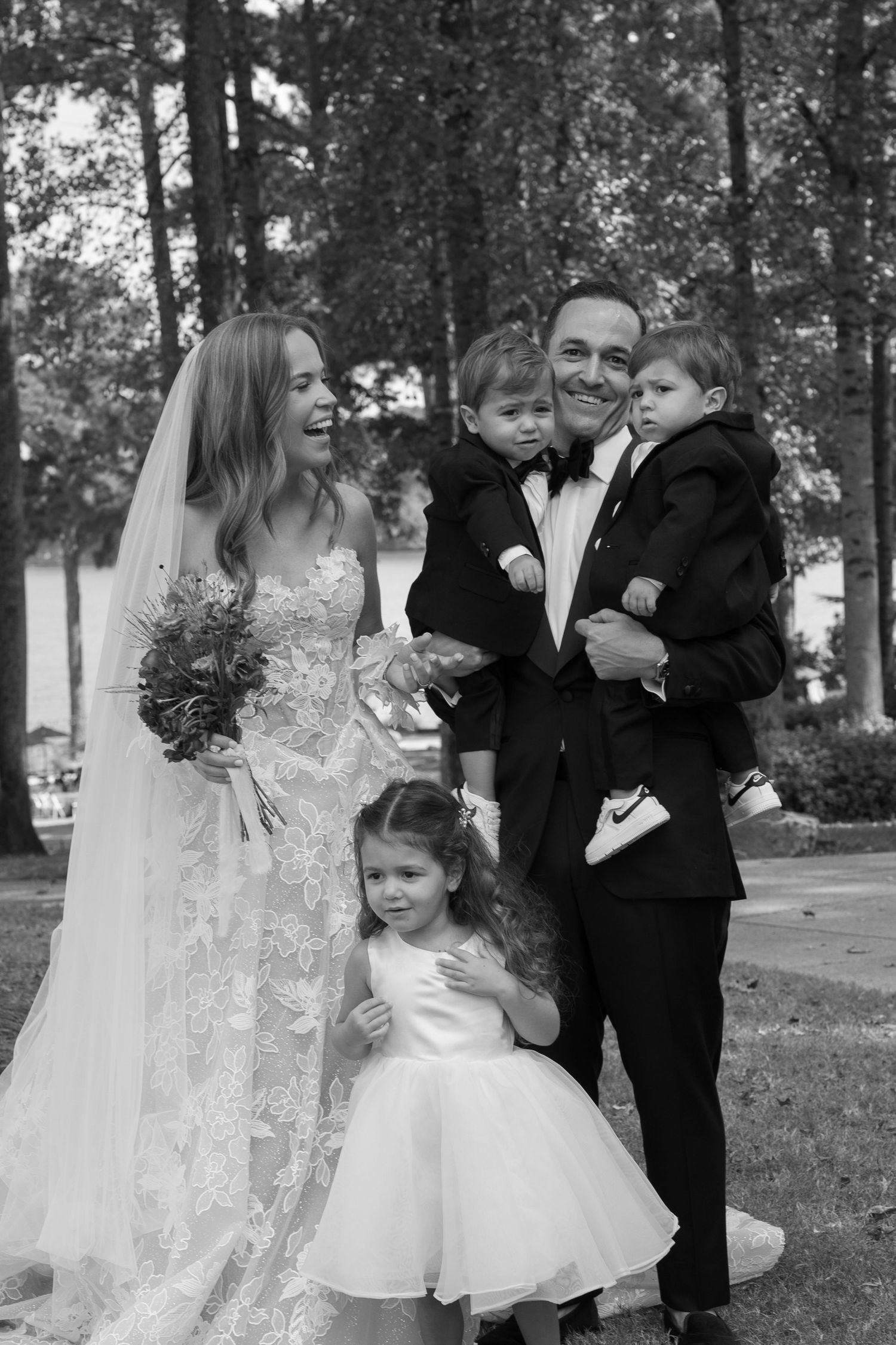 A joyful wedding portrait of a family group outdoors in formal attire.