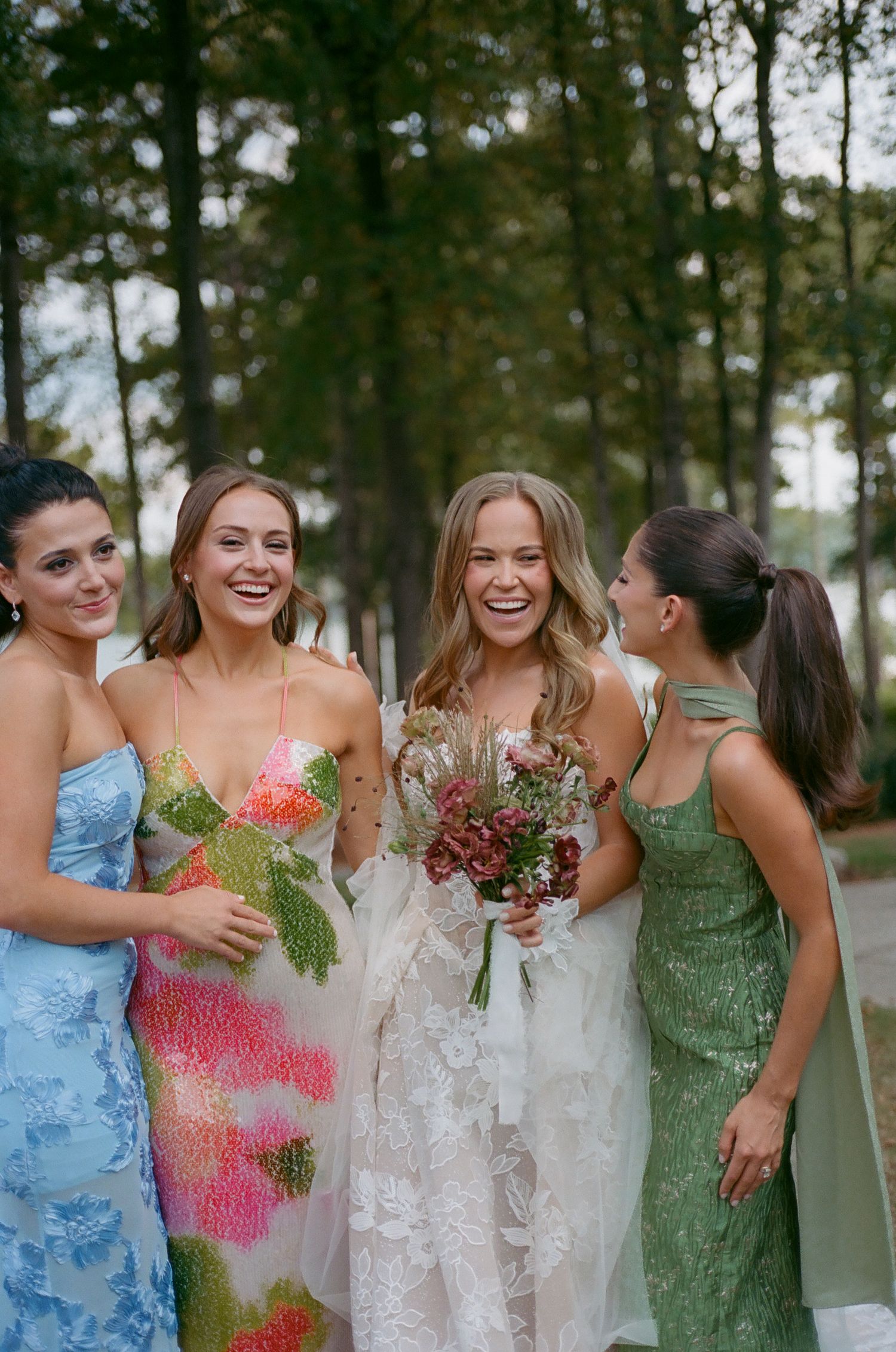 Bridesmaids in colorful dresses laughing together during wedding celebrations.