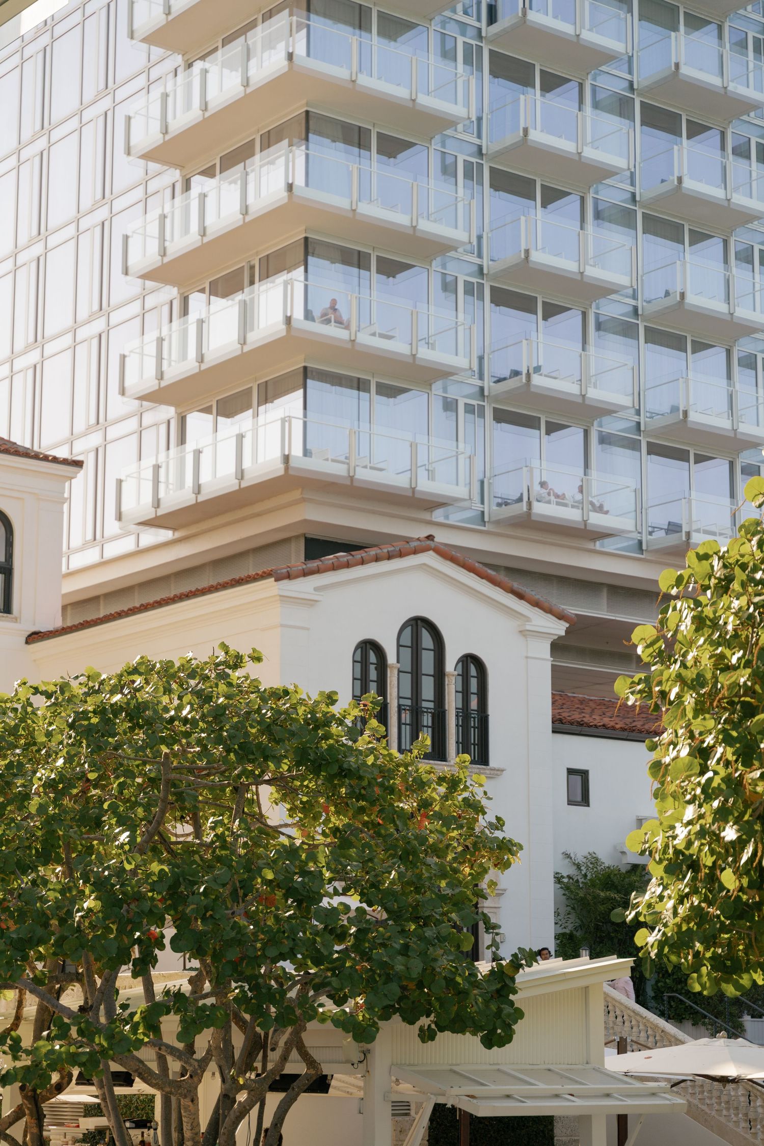 Modern luxury high-rise building with glass balconies and Mediterranean architectural details.