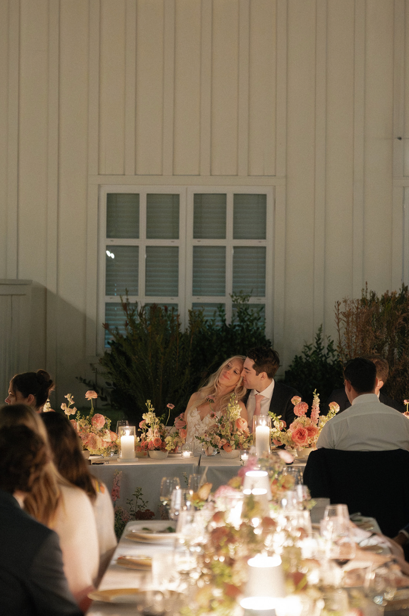 Intimate wedding reception dinner scene with candlelight and floral centerpieces.