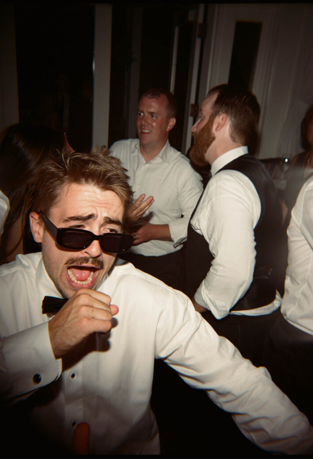Wedding guests in white shirts dancing and celebrating at a reception party.