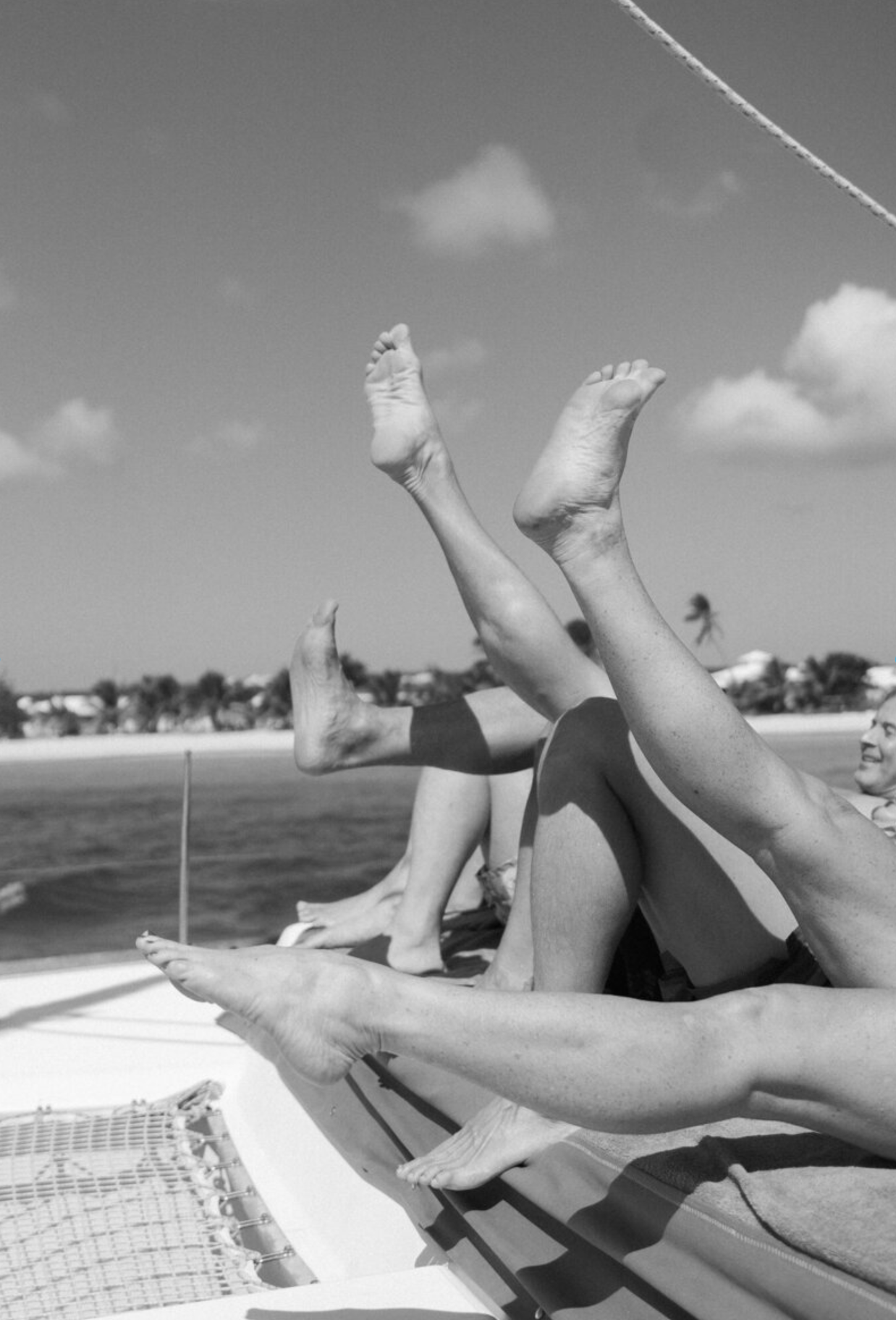 Relaxed feet and legs lounging on a boat deck against an ocean backdrop.