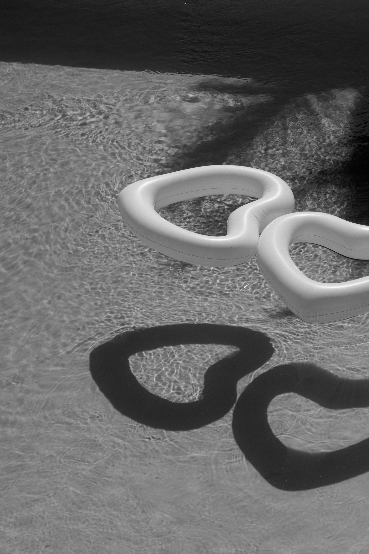 The image shows a pair of white handcuffs lying on a dark surface, casting a shadow.