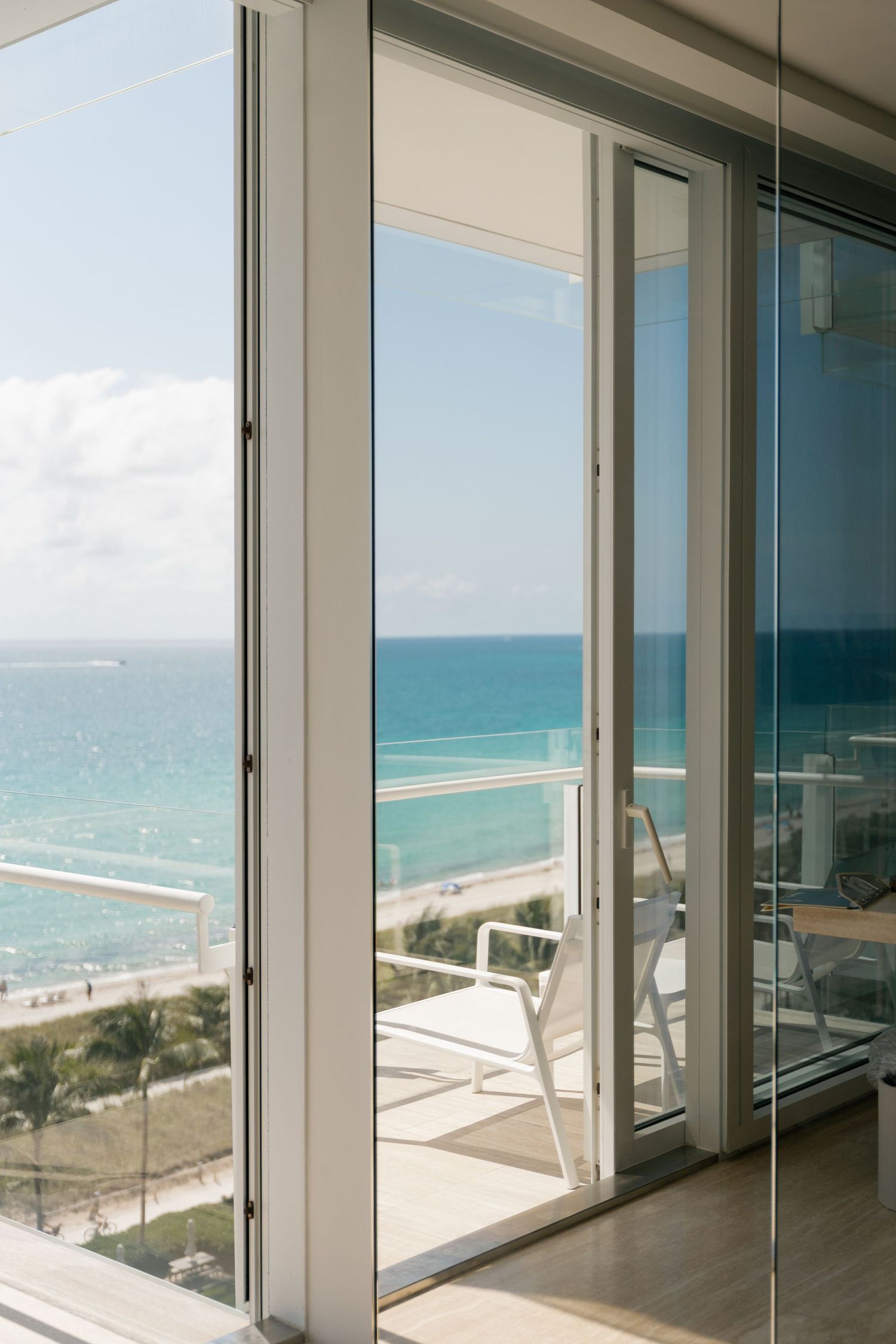 Floor-to-ceiling windows offering panoramic views of a turquoise ocean and beach.