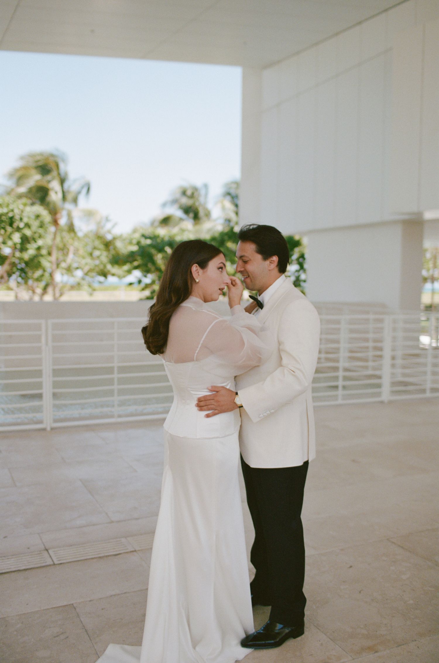 Wedding couple sharing an intimate moment in a bright outdoor covered space.